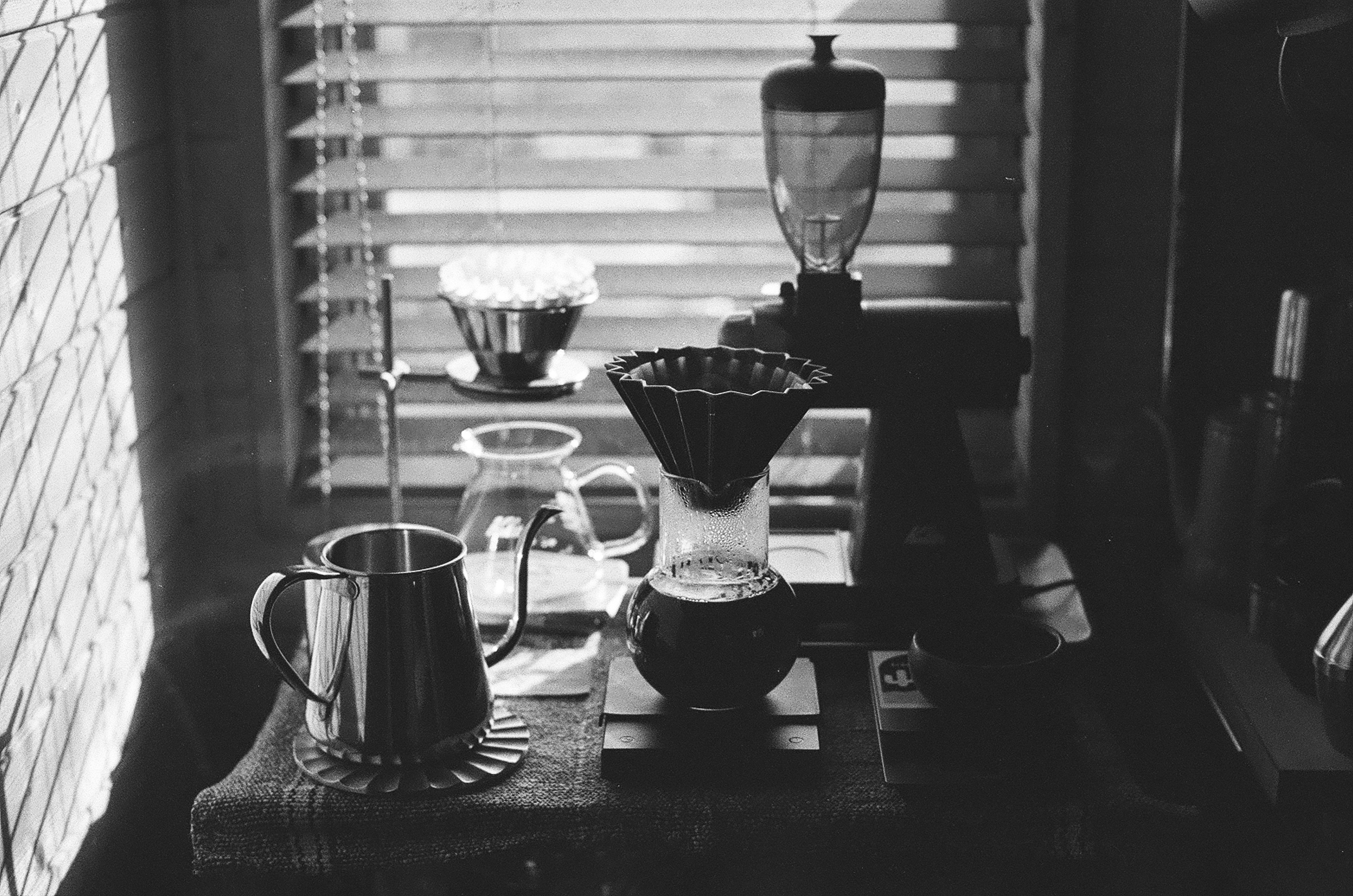 A silver kettle and dripper set on a wooden table with coffee equipment