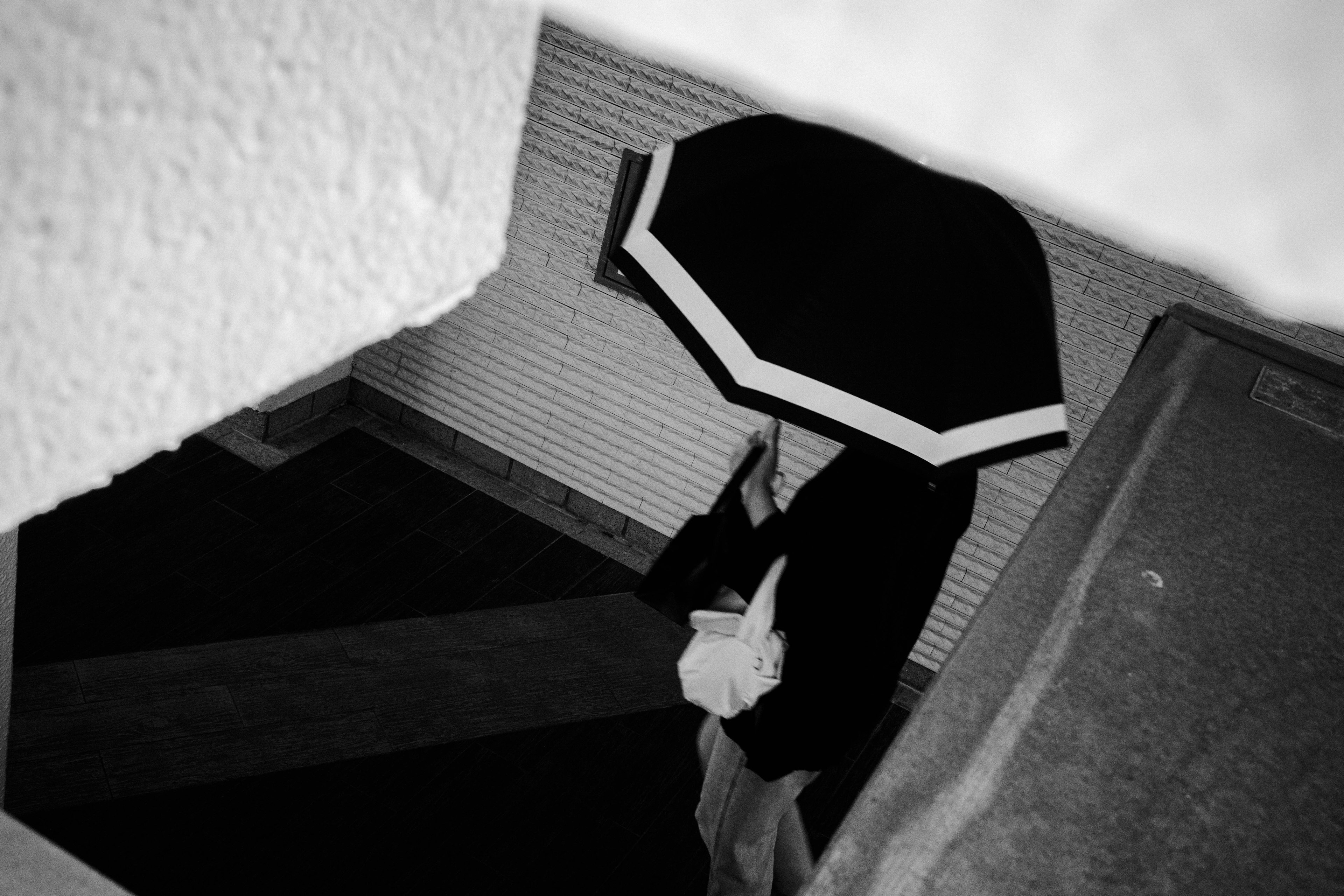 Une personne tenant un parapluie descendant des escaliers en noir et blanc