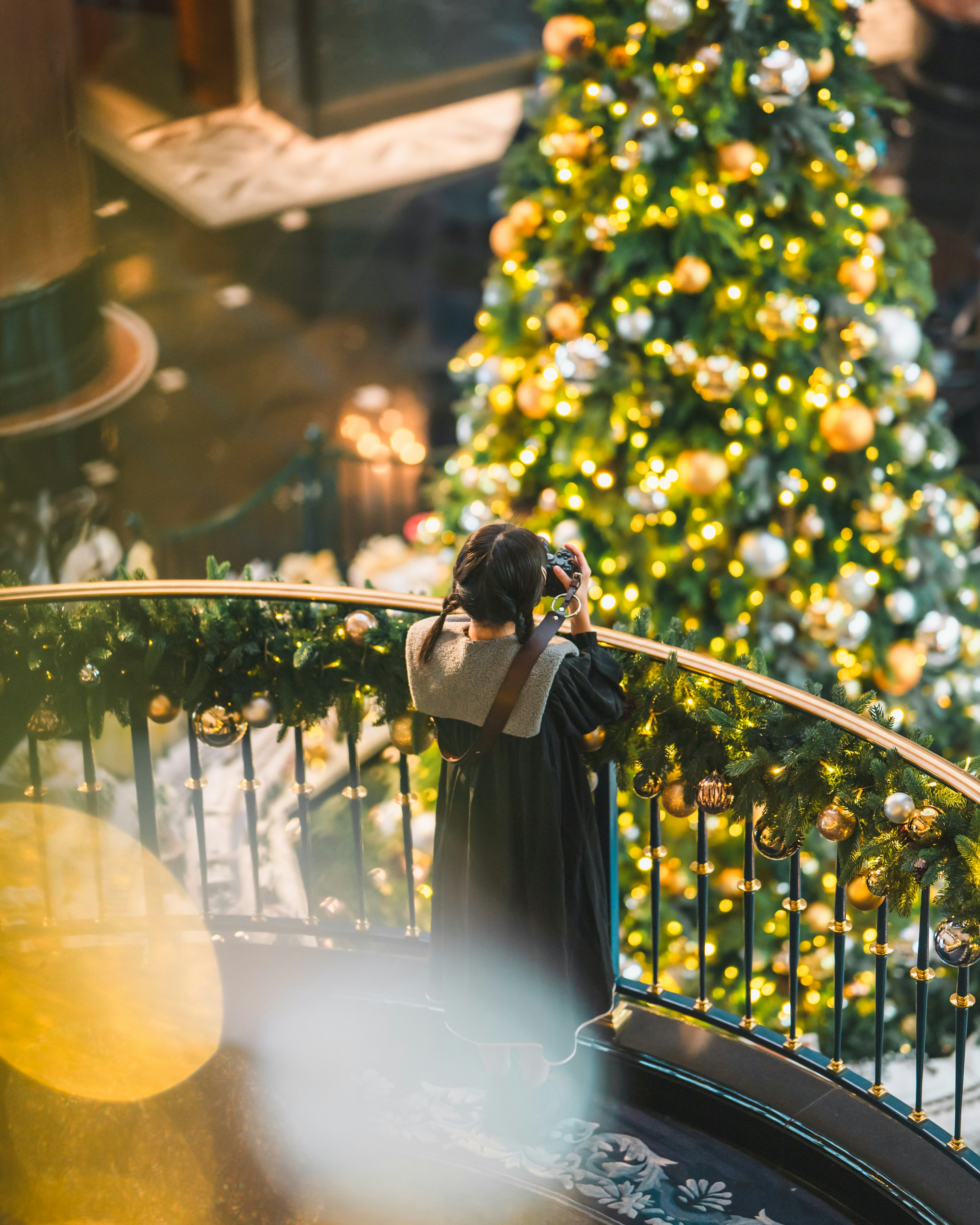 クリスマスツリーの前で写真を撮る女性の後姿