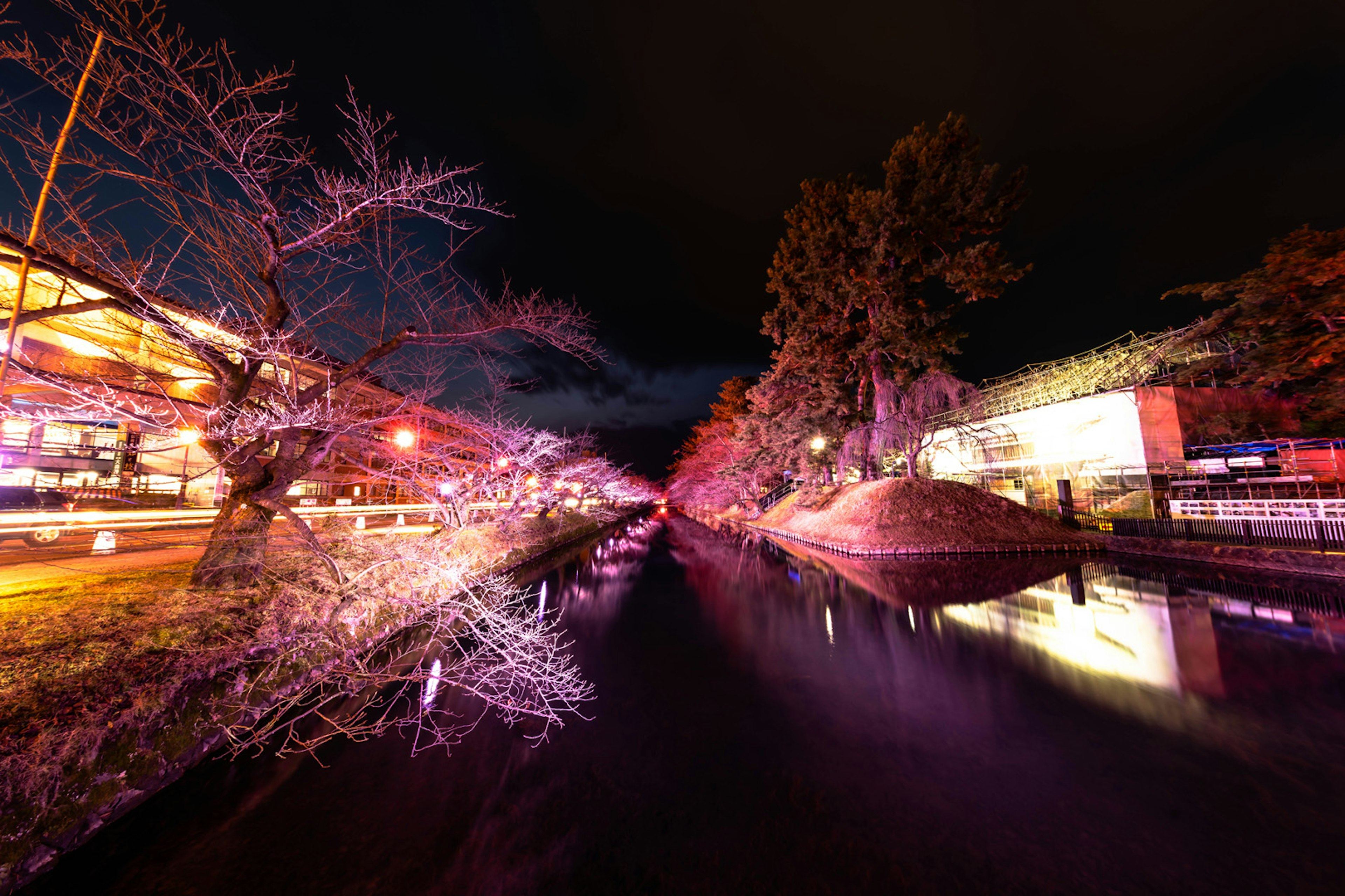 夜の川沿いに色とりどりのライトが輝く風景