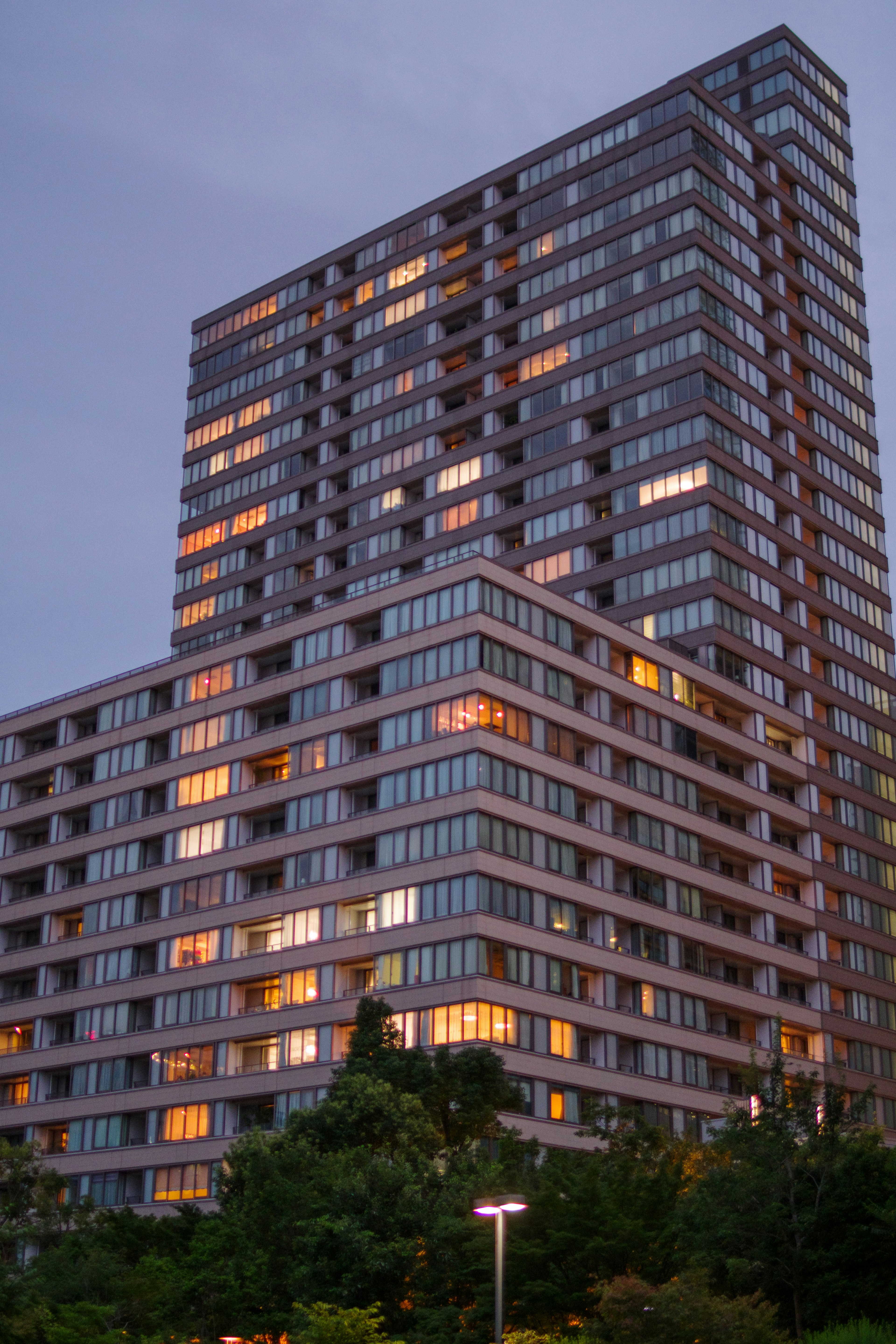 Immeuble moderne en hauteur à la tombée de la nuit avec des fenêtres illuminées