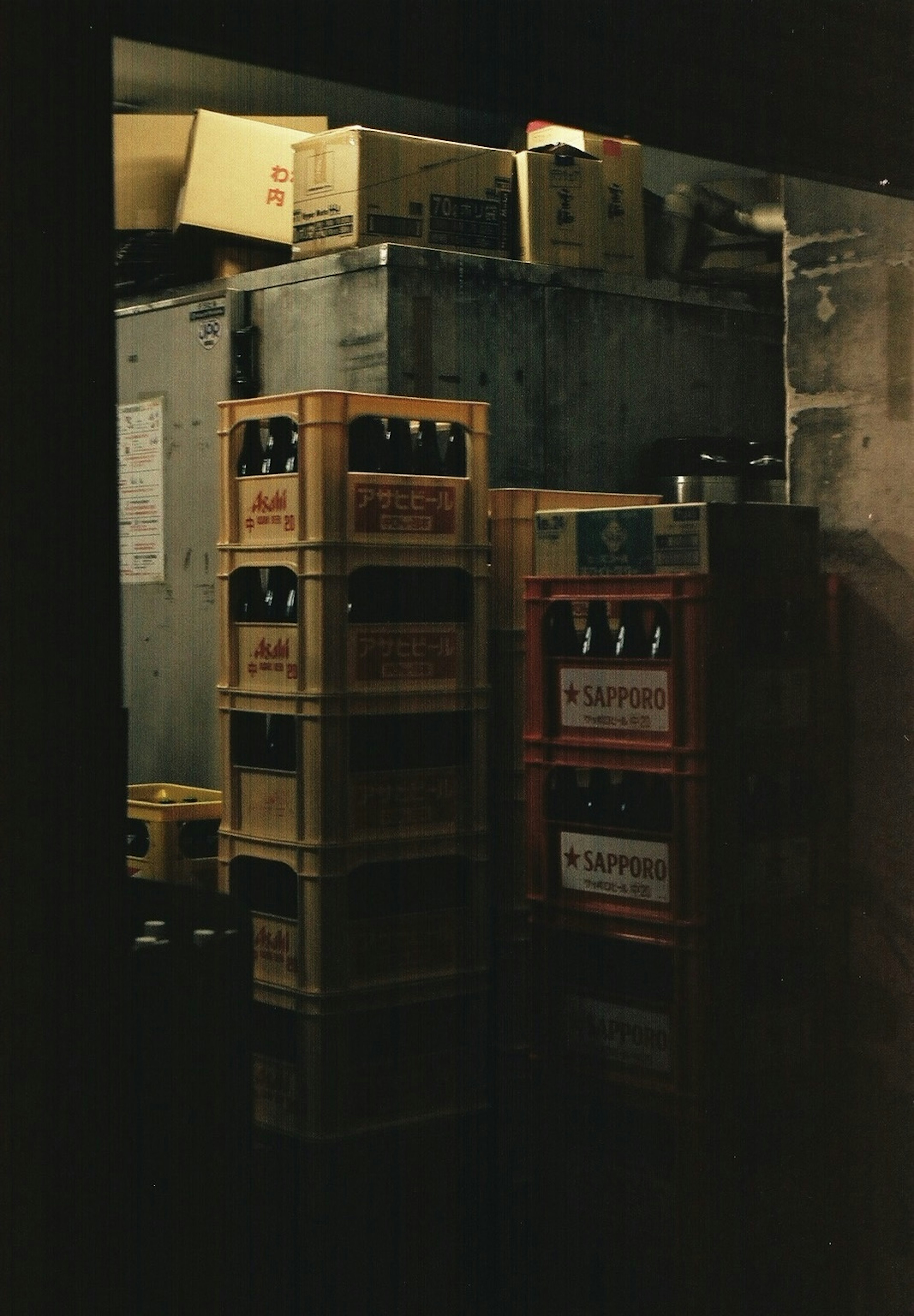 Cajas de madera y botellas apiladas en una habitación de almacenamiento oscura