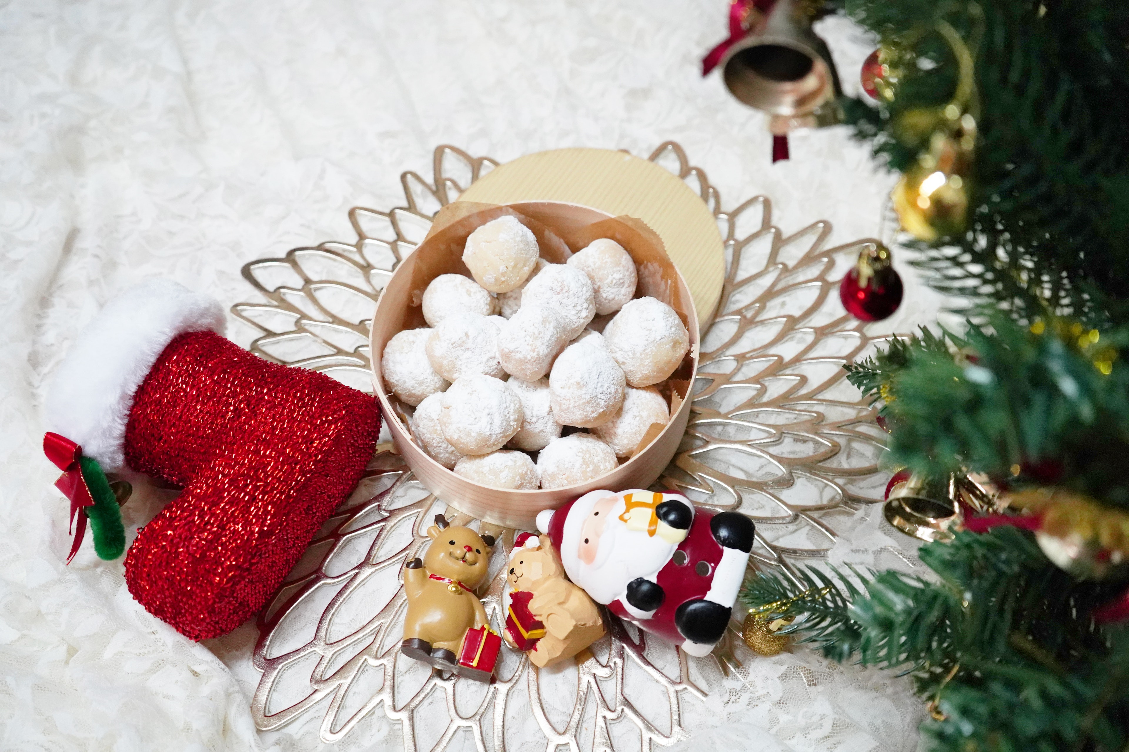 A bowl of white candies on a decorative tray with Christmas ornaments and a Santa figure