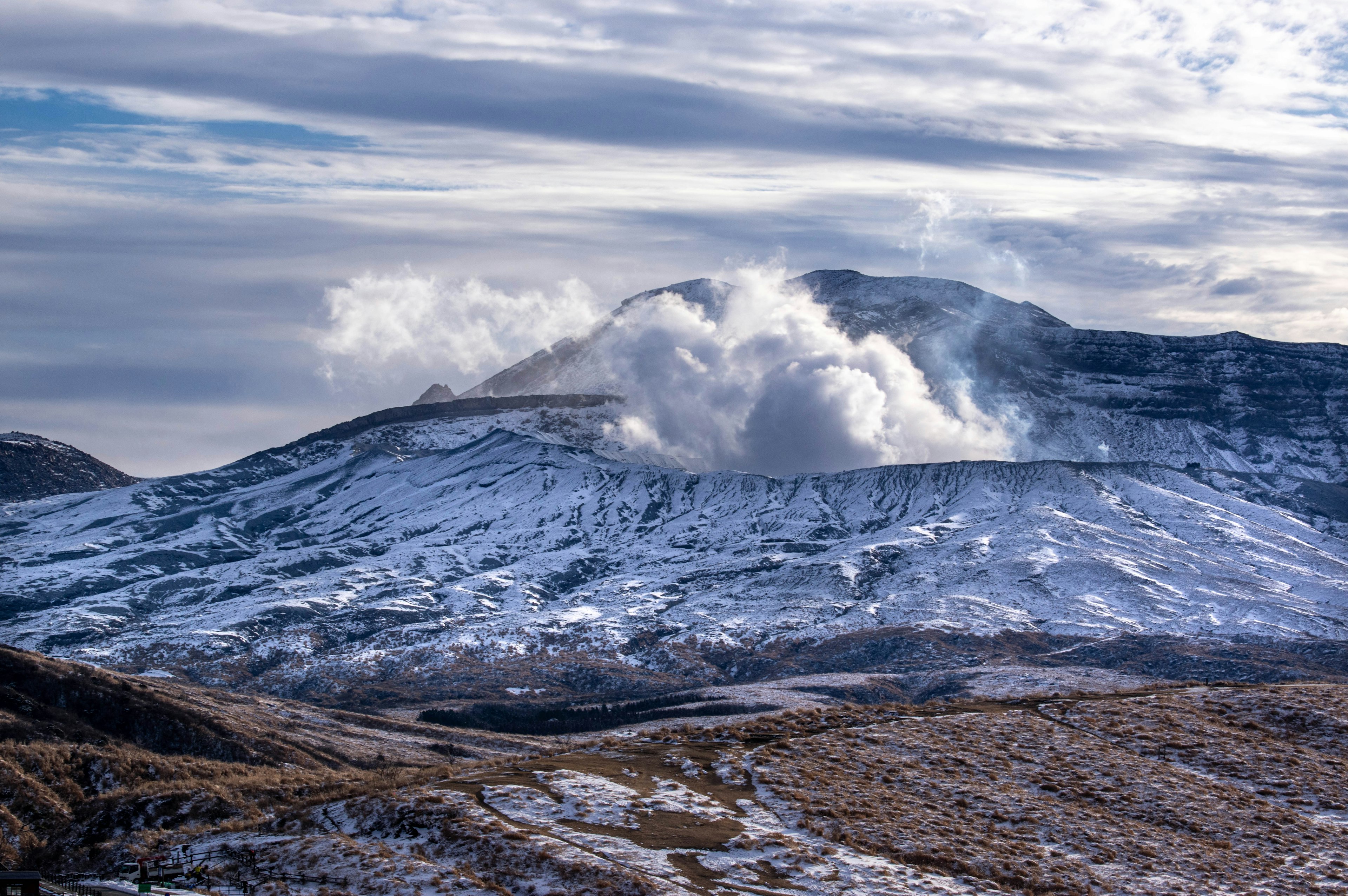 Snow-covered volcano with smoke rising from the crater