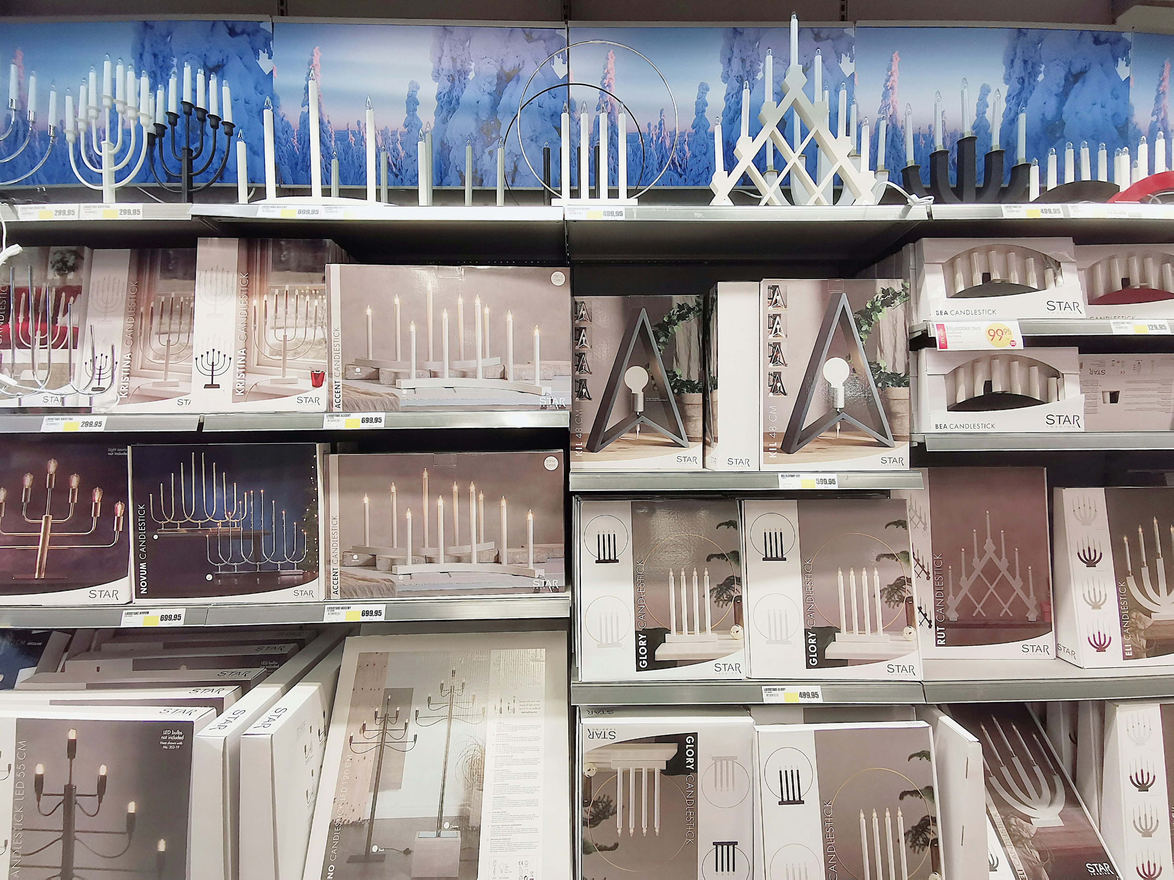 Image of shelves displaying white and beige candle holders with a blue decorative background