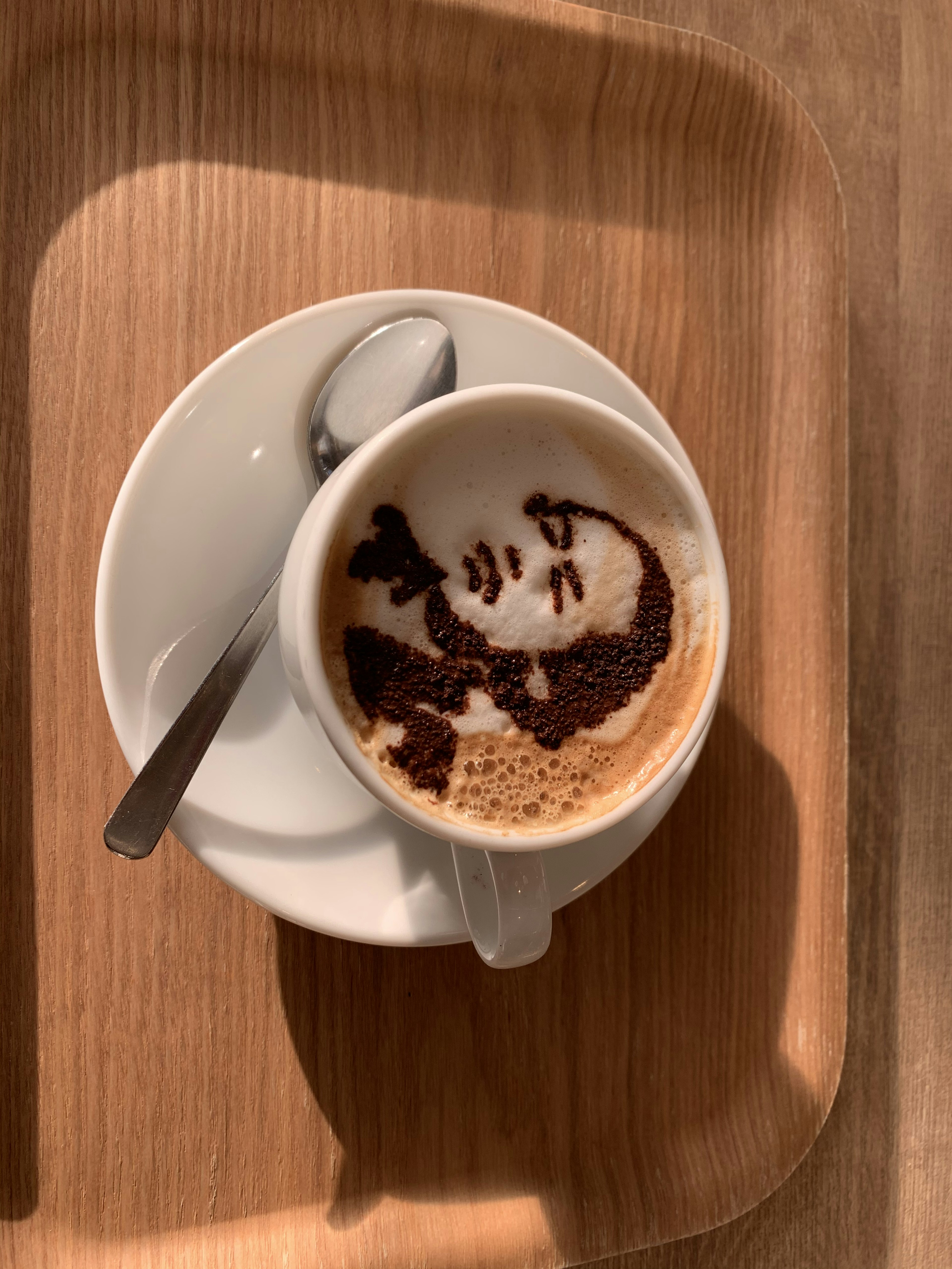 Imagen de una taza de café con un diseño artístico de cara en la superficie