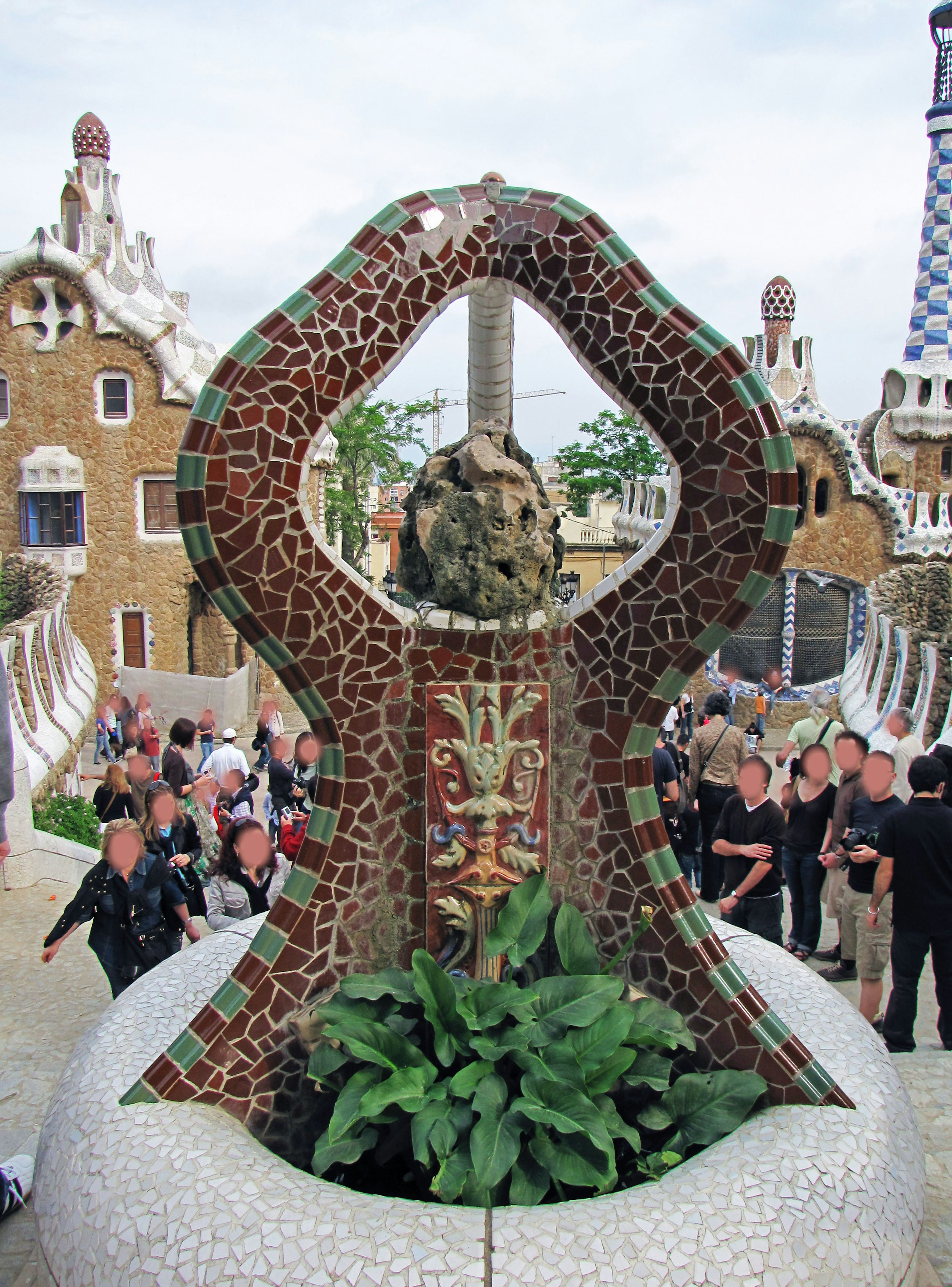 Escultura de mosaico única en el Parque Güell con turistas alrededor