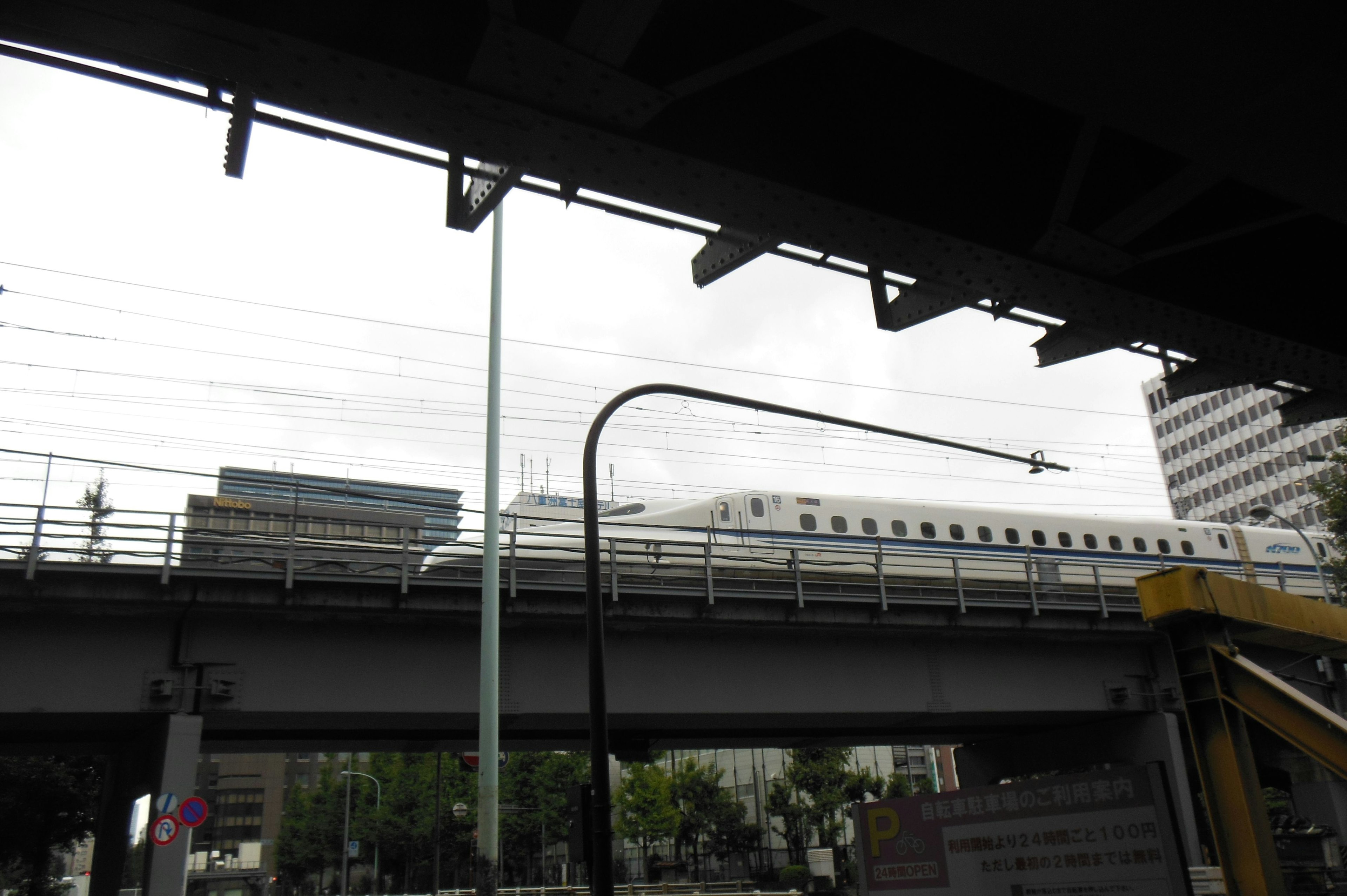 Shinkansen yang melaju di rel tinggi dengan bangunan di latar belakang