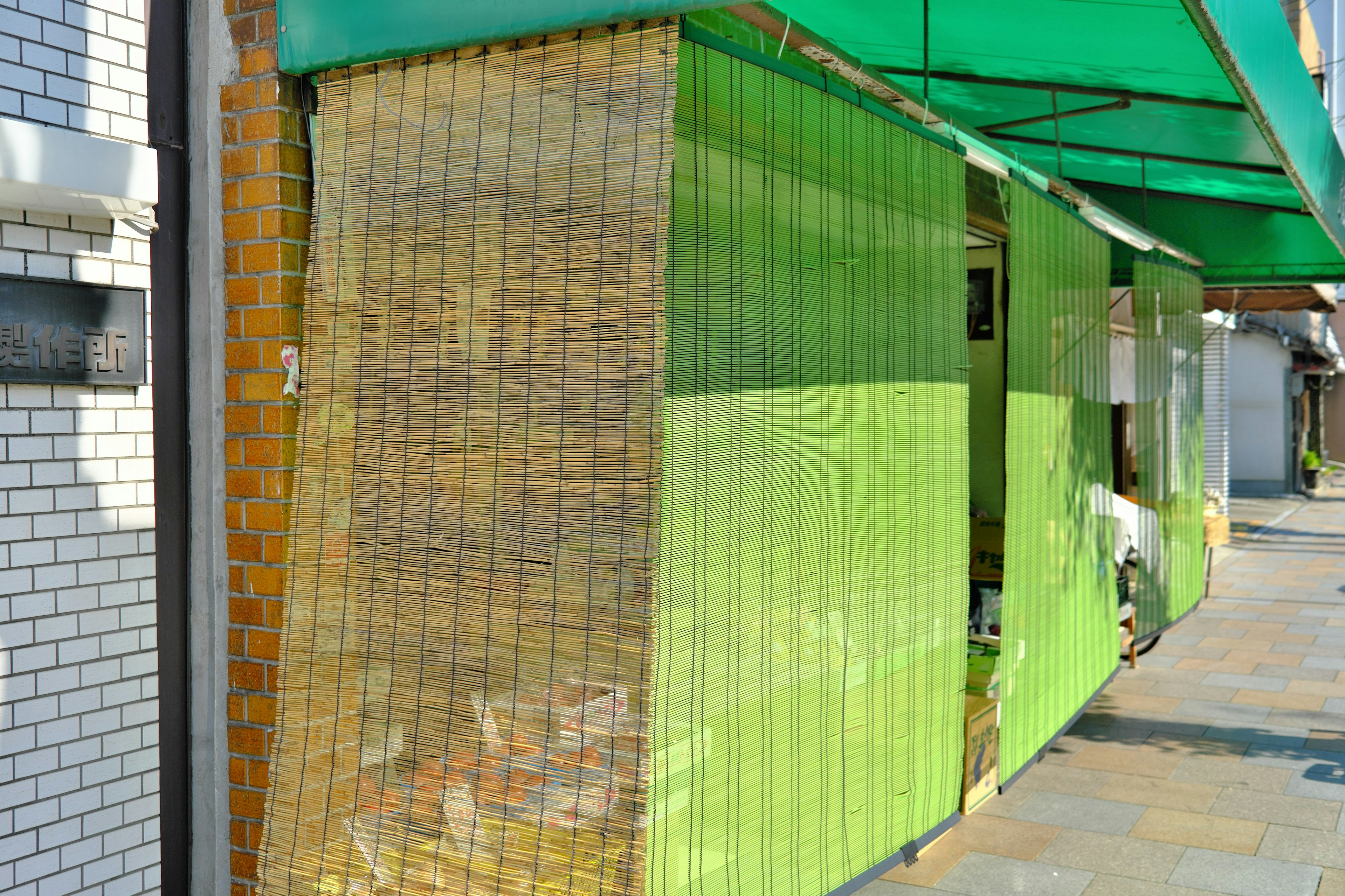 Exterior de una tienda con una pared verde y una cortina de bambú