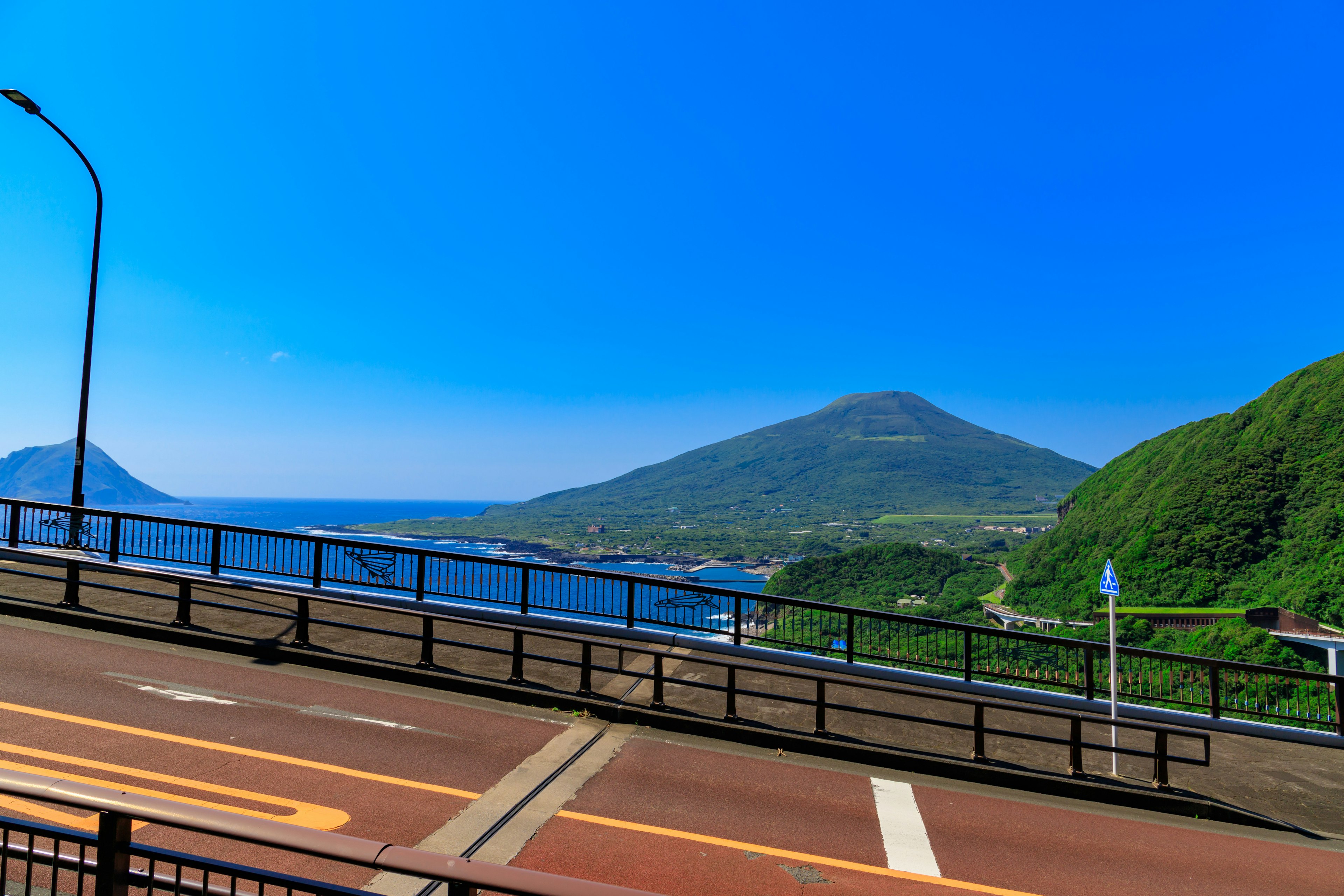 Vue côtière avec un ciel bleu et des collines vertes