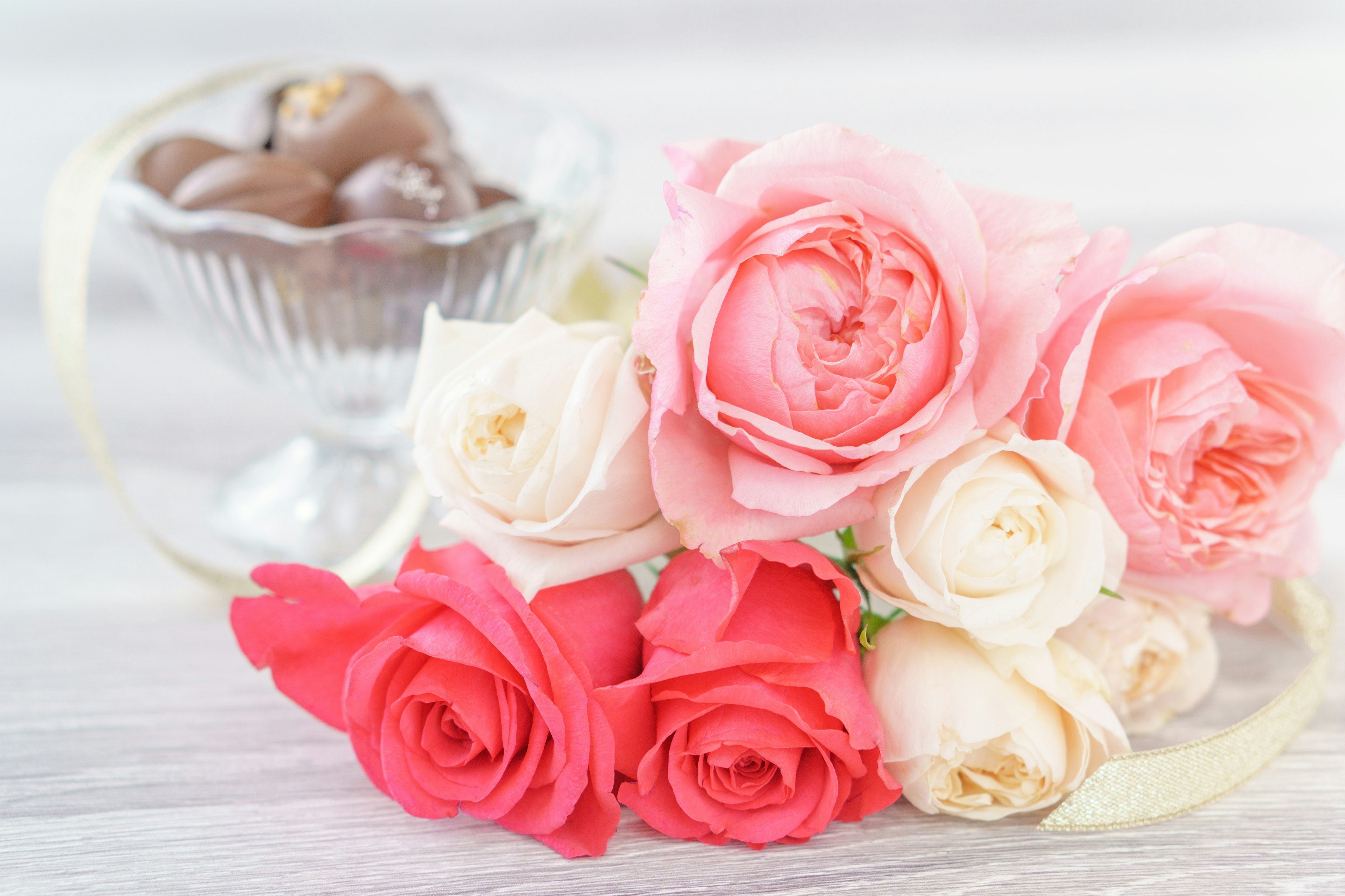 ピンクと赤のバラの花束とガラスの器に入ったチョコレート