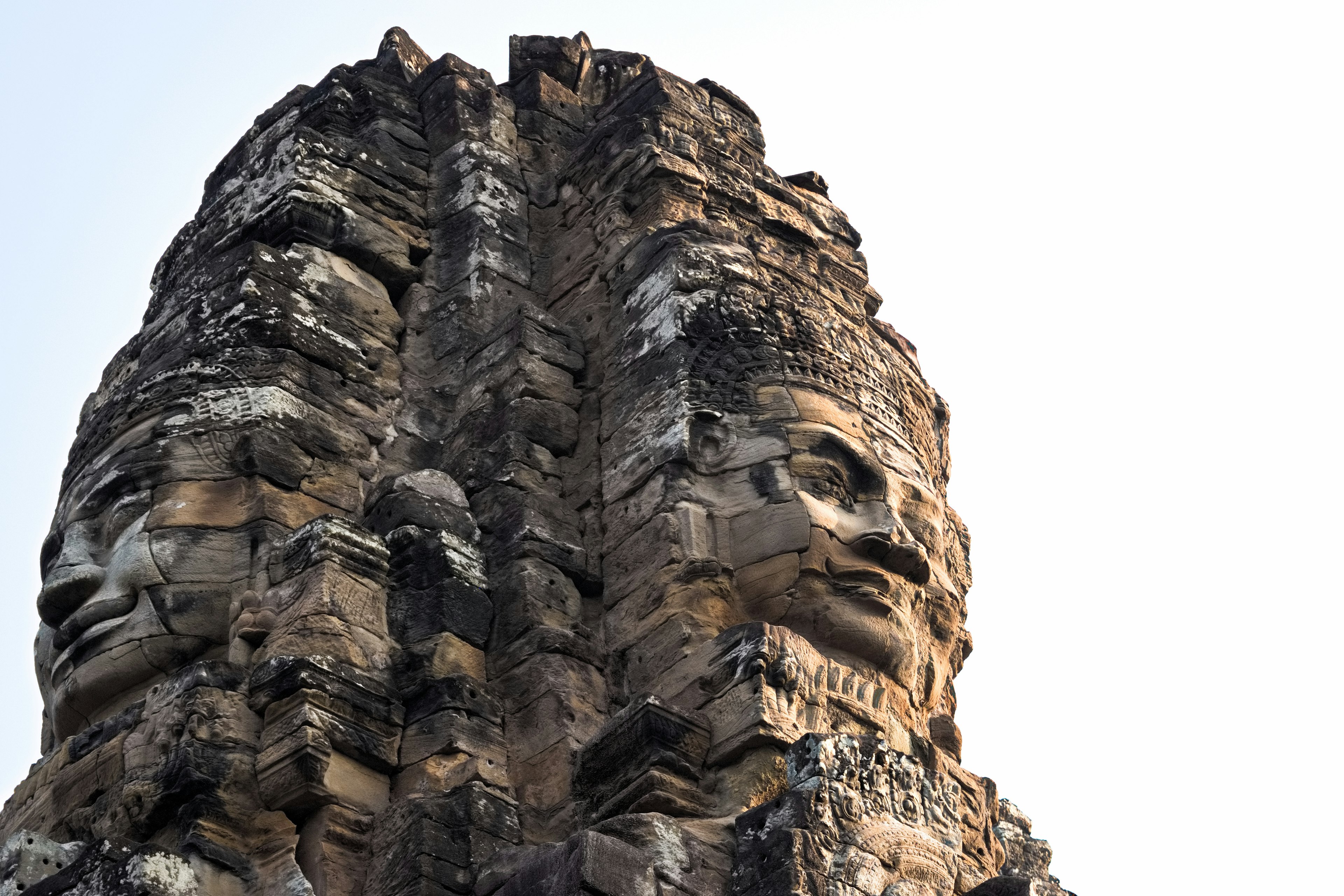 Primer plano de las caras de piedra del templo Bayon mostrando dos rostros distintos