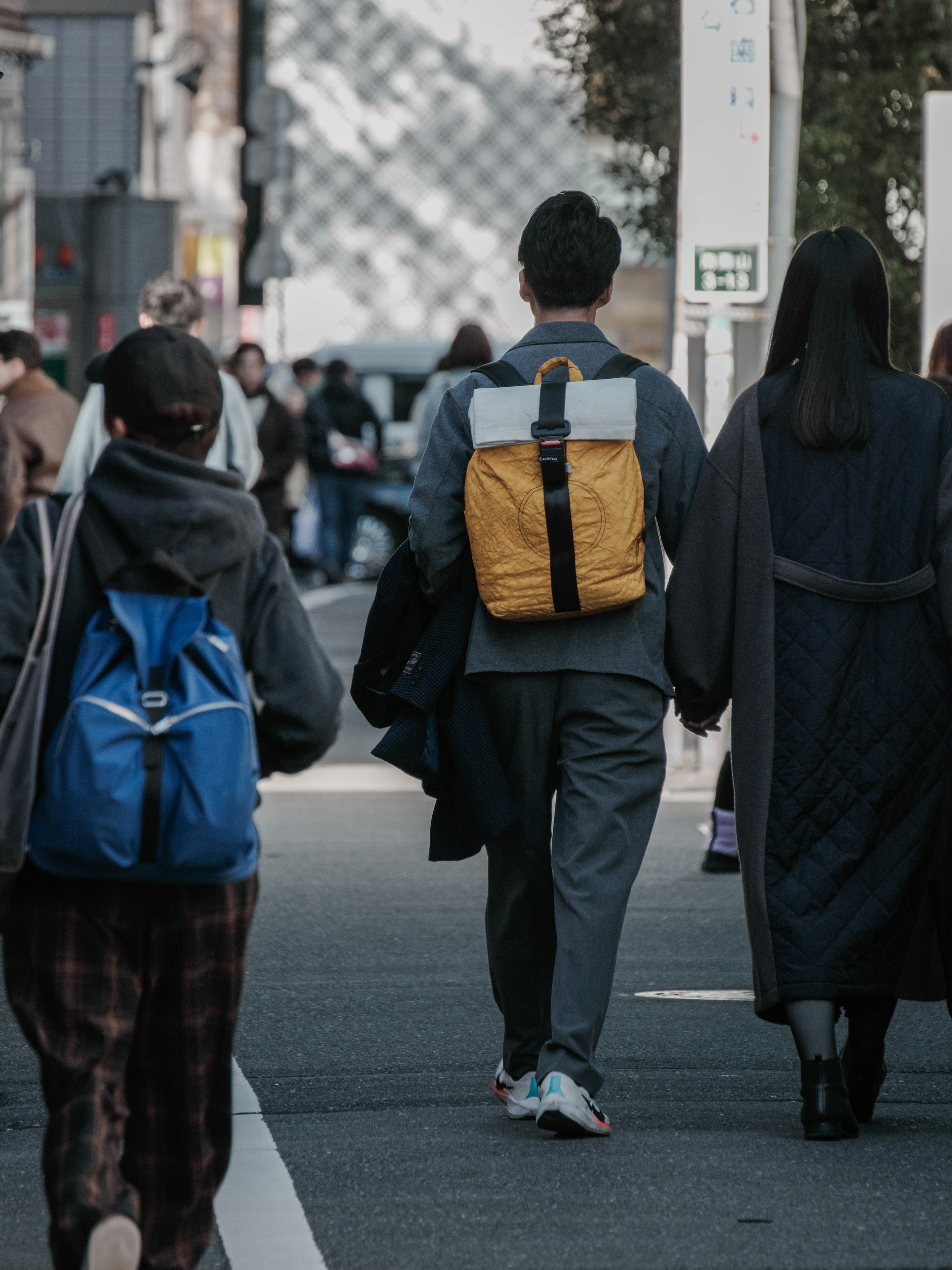 Persone che camminano per strada un uomo con uno zaino giallo