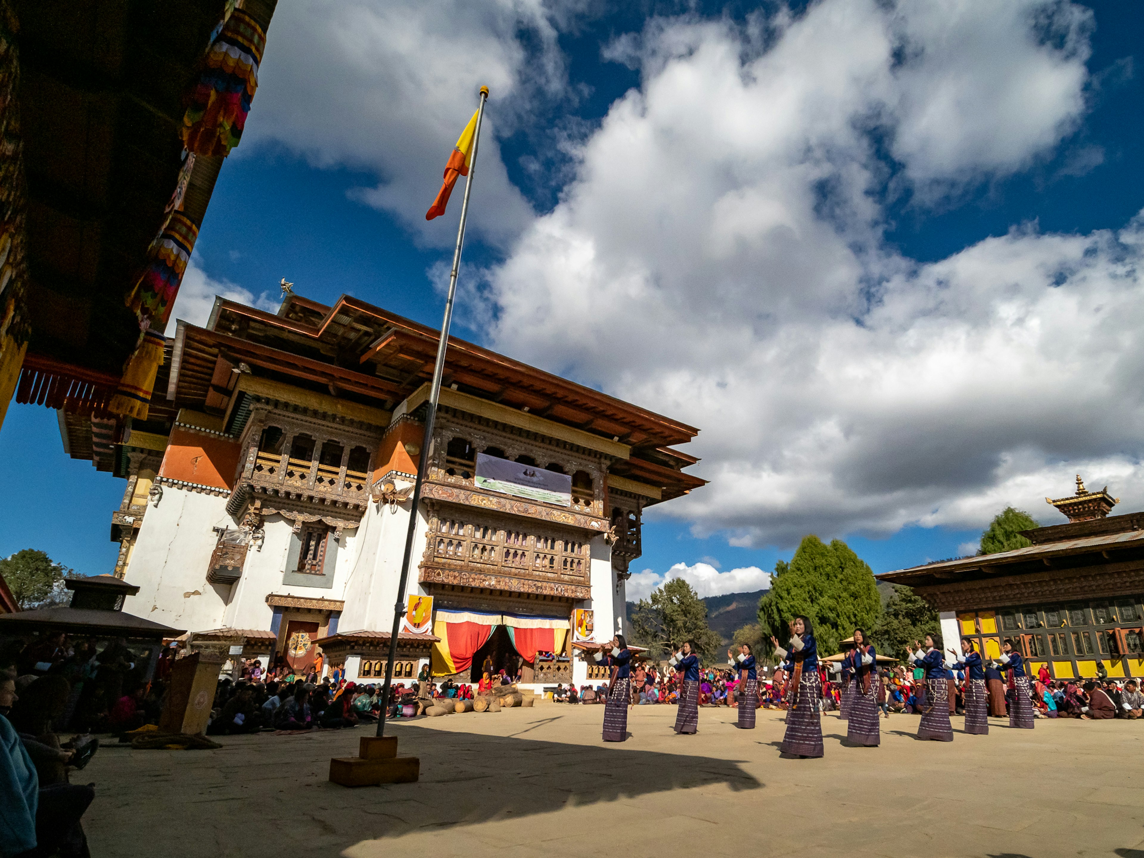 Traditionelles bhutanisches Festival unter einem schönen blauen Himmel mit Tänzern und historischen Gebäuden