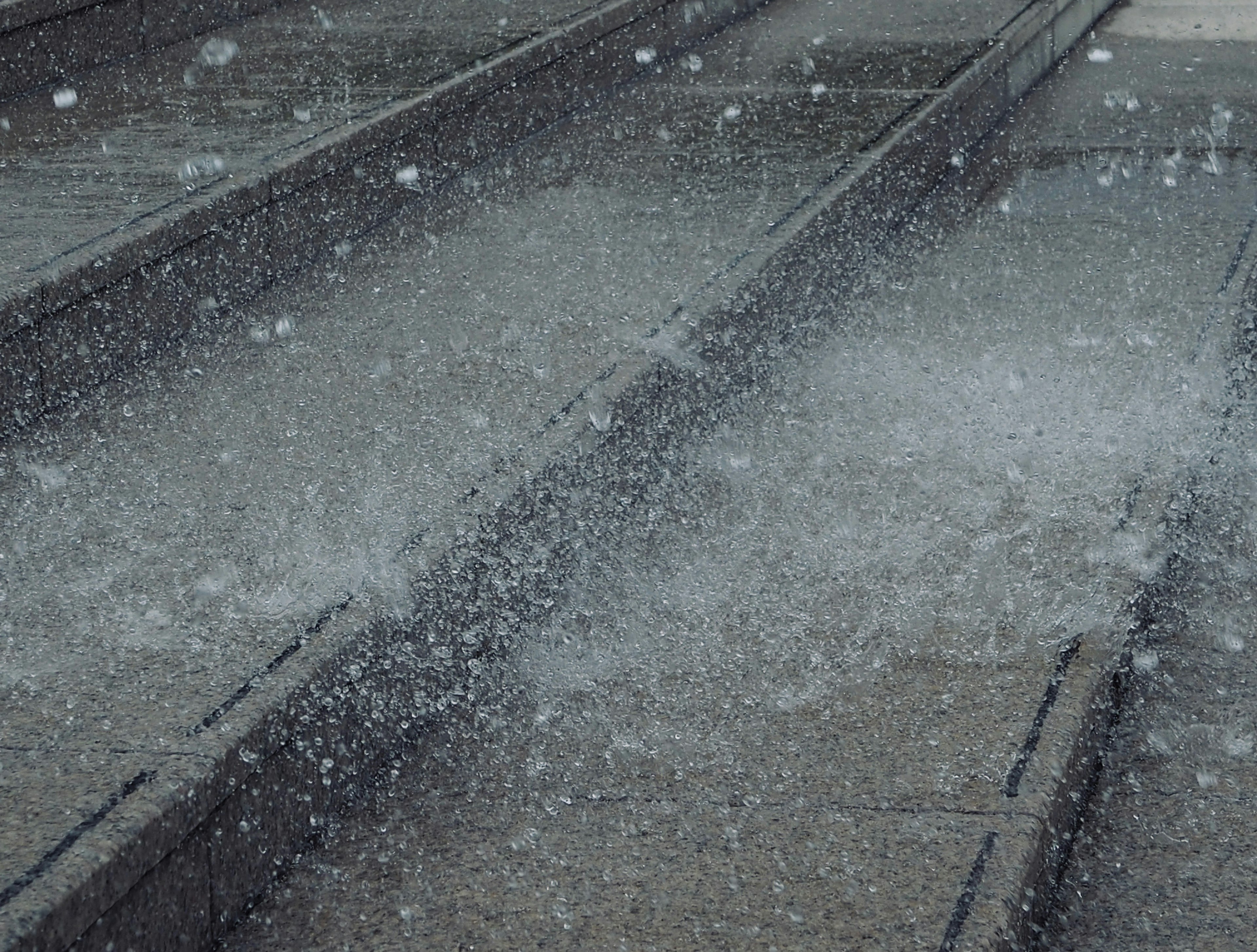 Parte di binari ferroviari con schizzi d'acqua sotto la pioggia