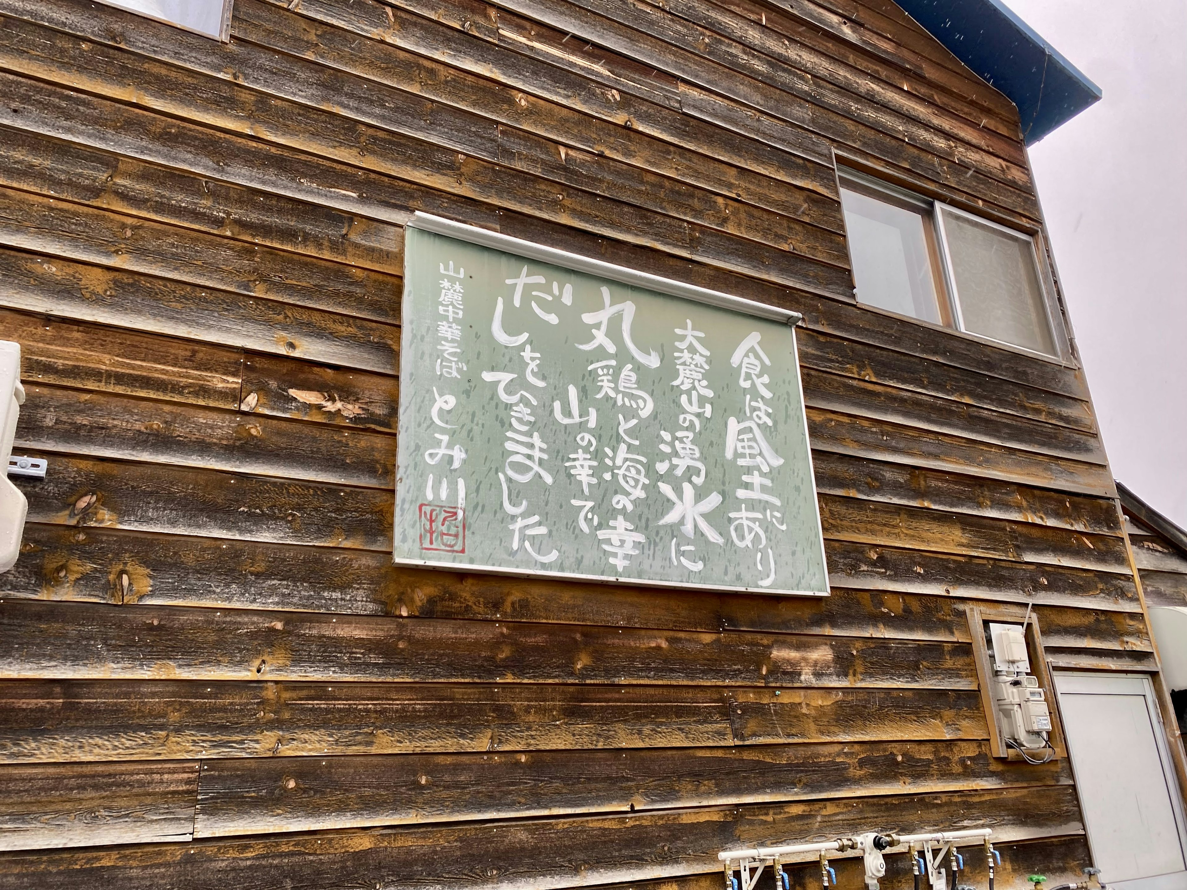 木の壁に掲示された日本語の看板がある風景