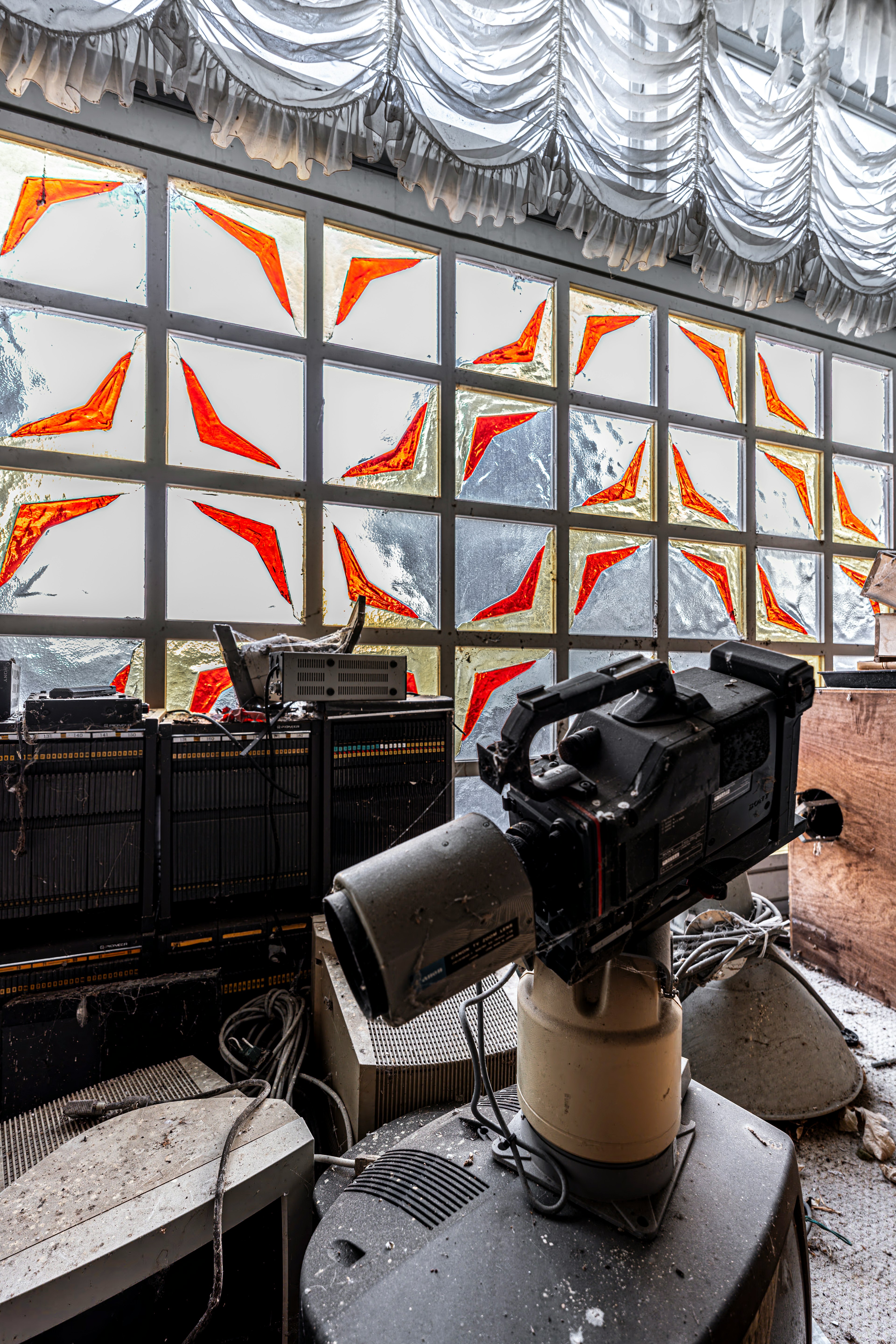 Abandoned room featuring a camera and colorful glass window