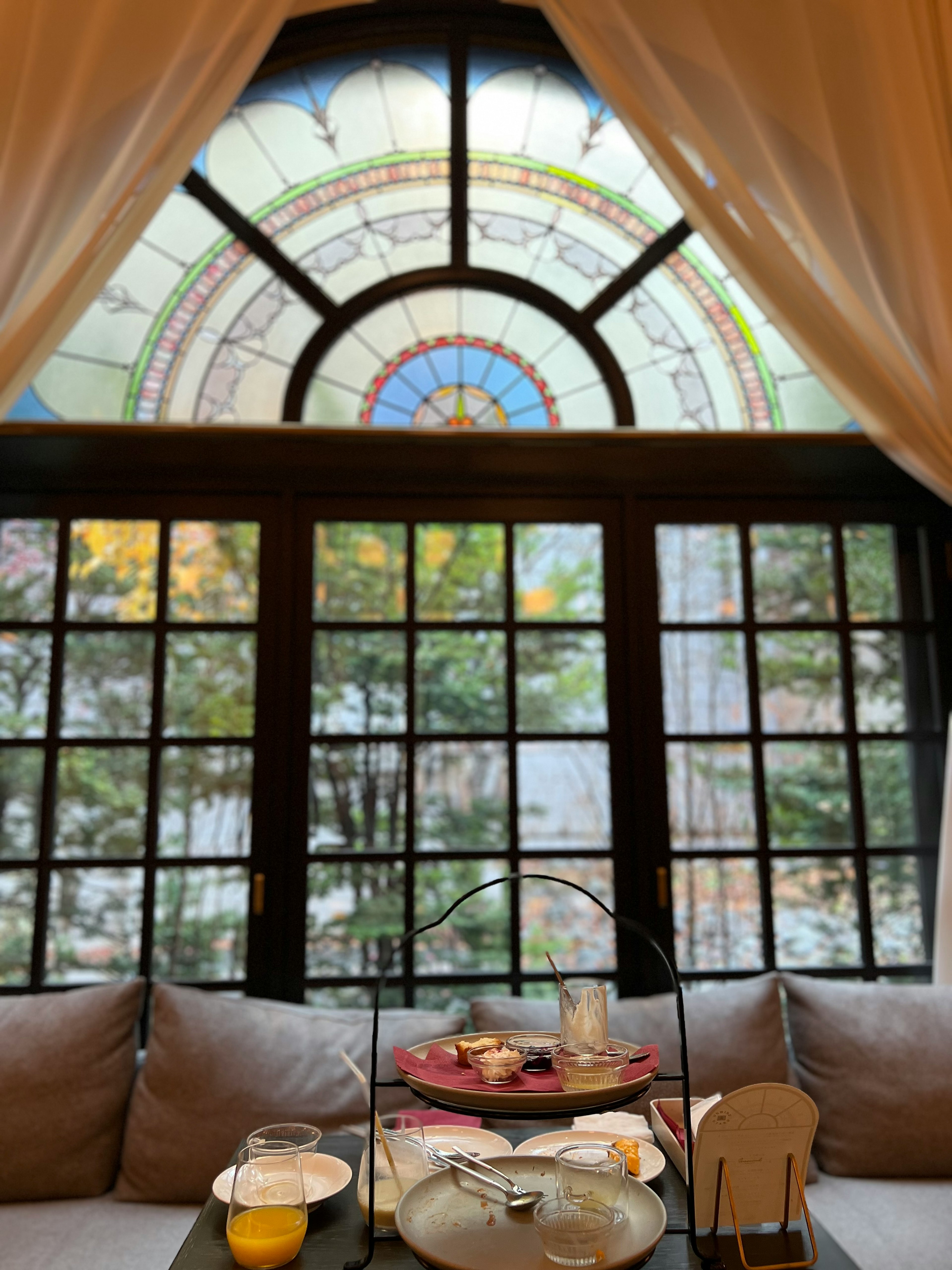 Beautiful stained glass window overlooking colorful trees with a table set for light snacks