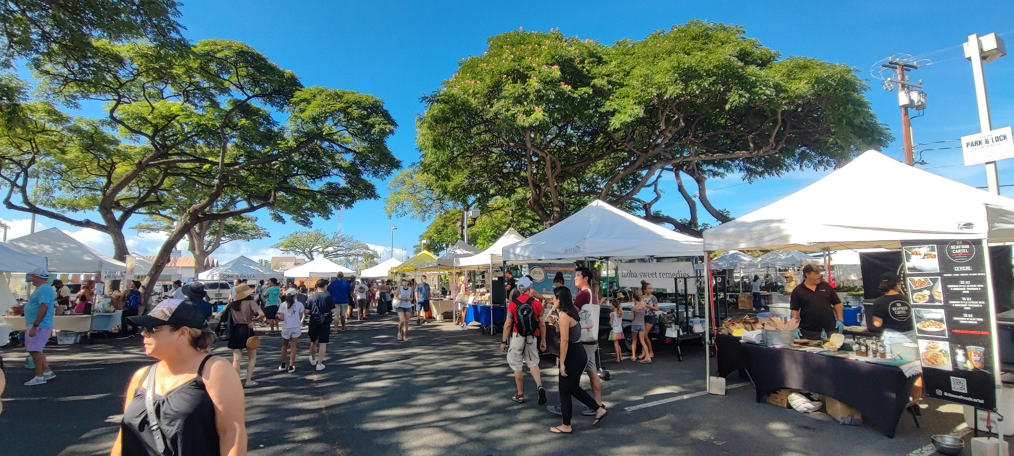 A vibrant market scene with white tents and people under a clear blue sky