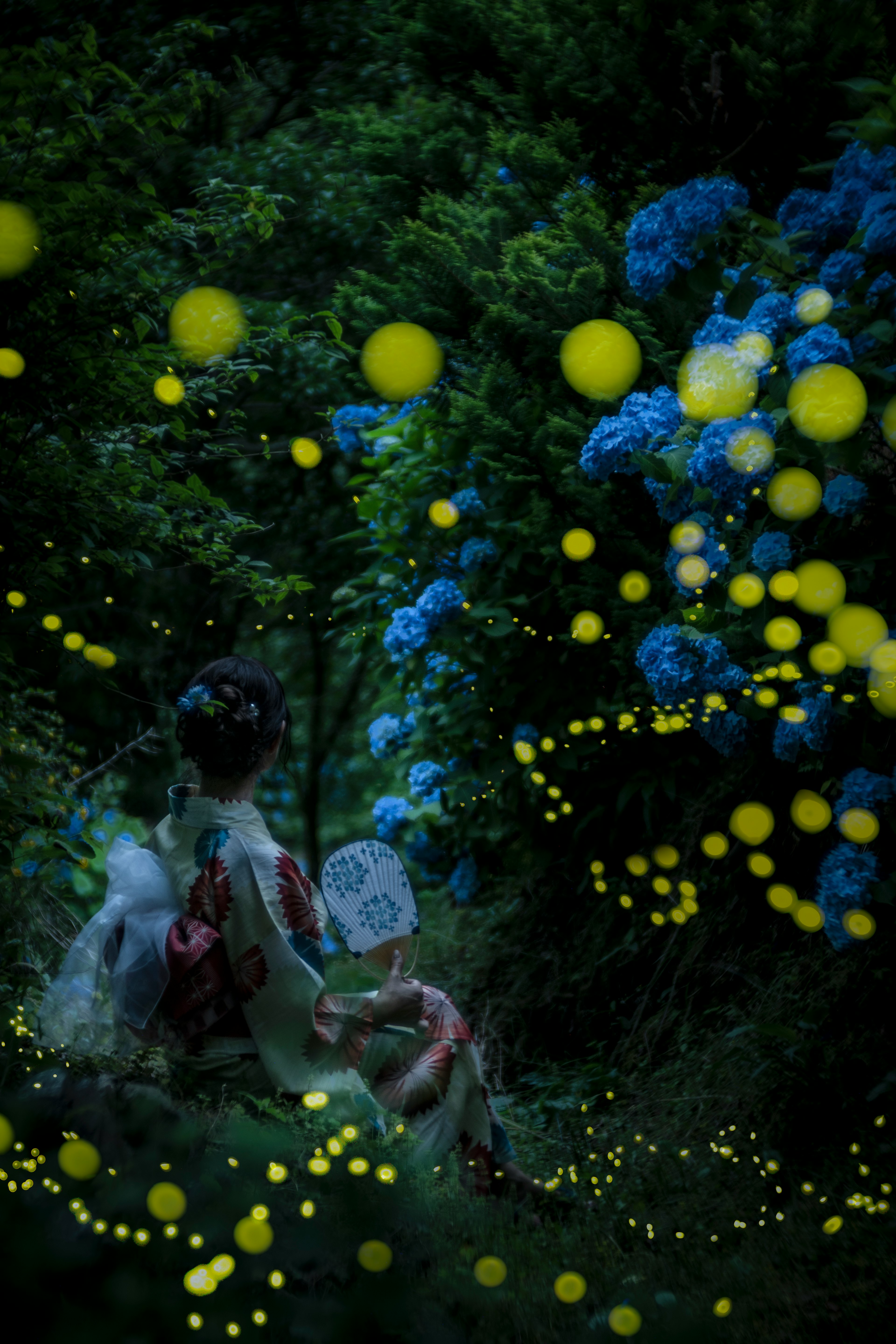 Una mujer en kimono sentada en un jardín místico con flores azules y luces amarillas brillantes