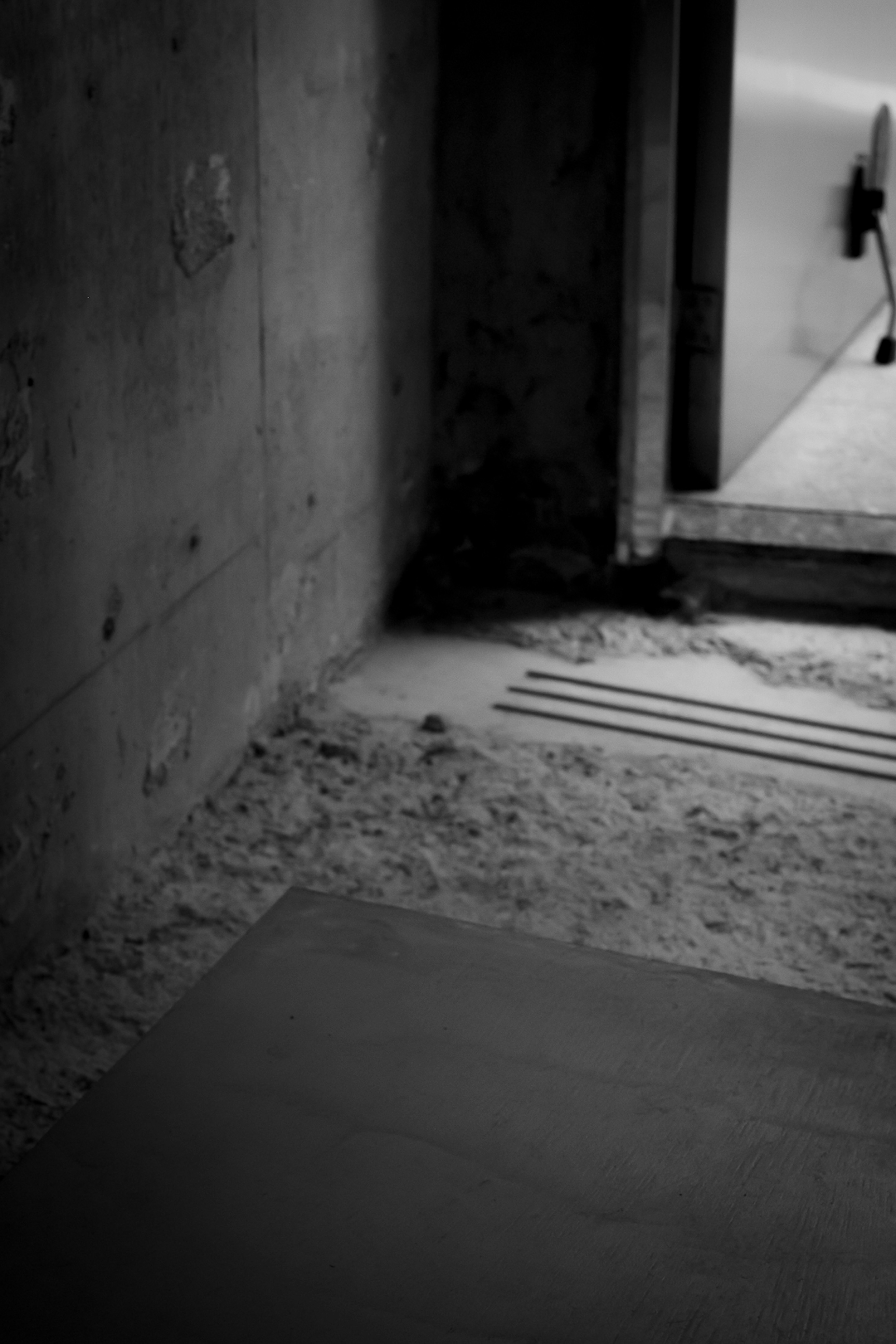 Photo of a room entrance featuring concrete walls and a sandy floor