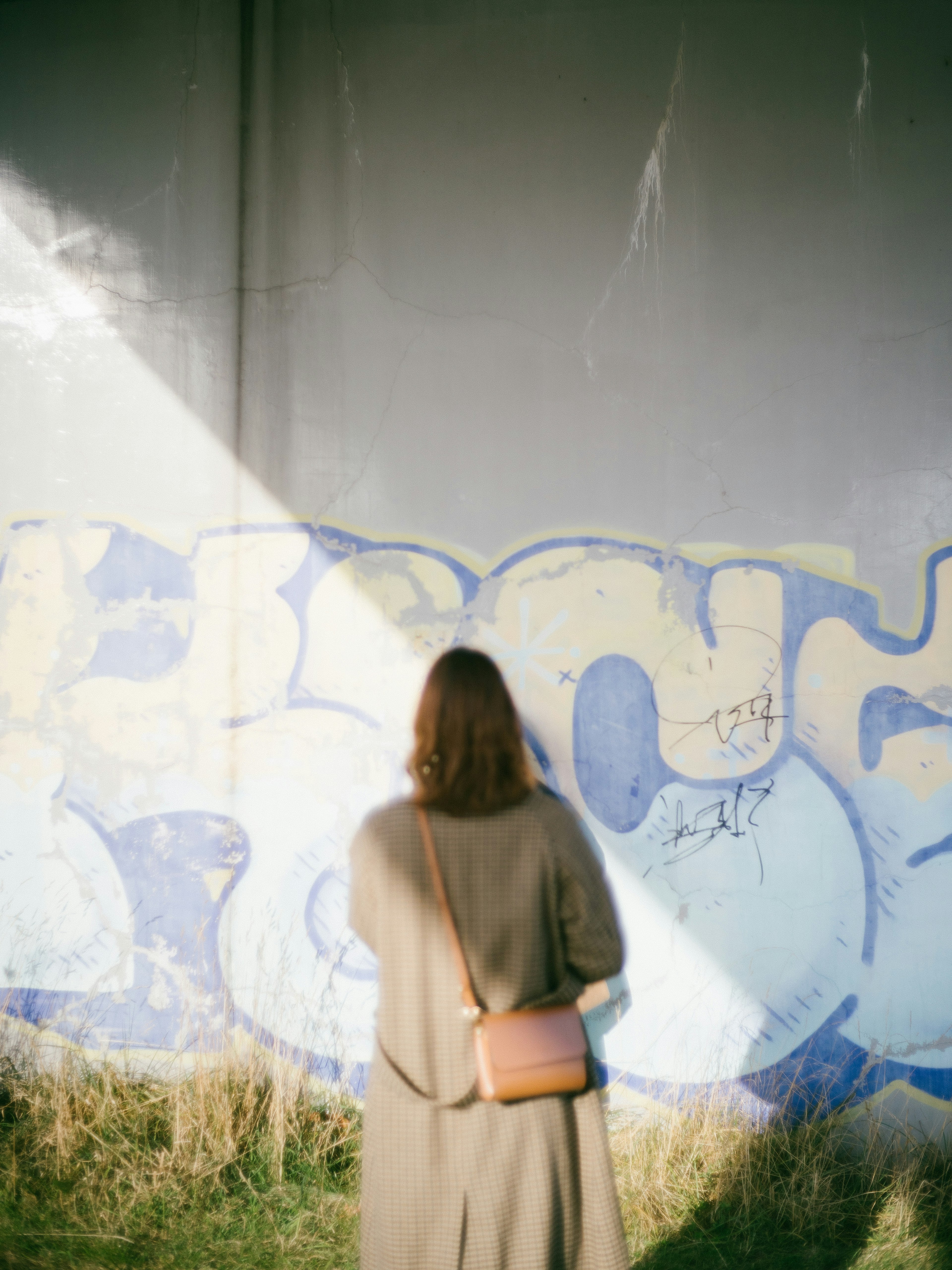 Una mujer mirando una pared de graffiti azul