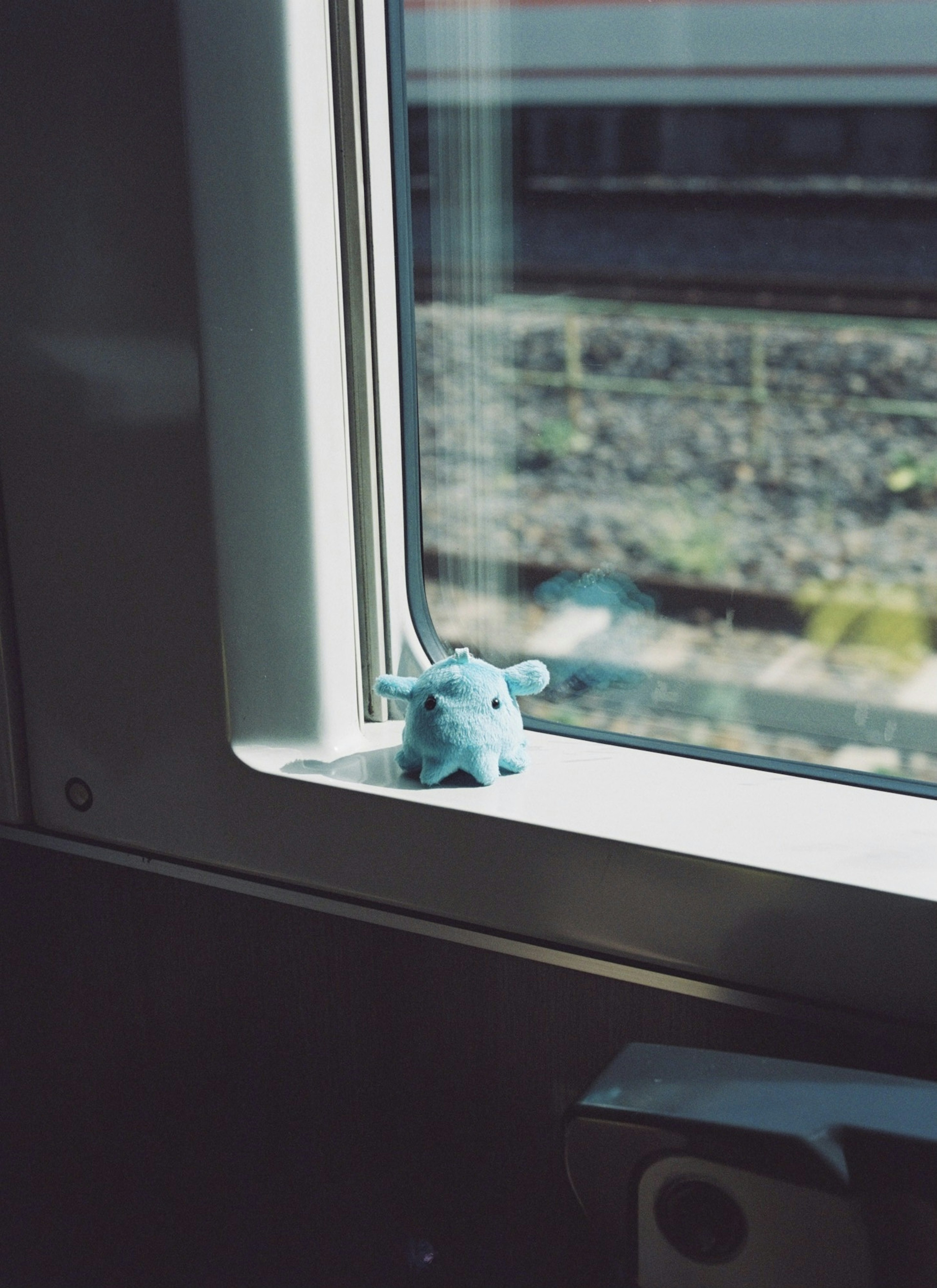 Une petite figurine d'animal bleu assise près de la fenêtre