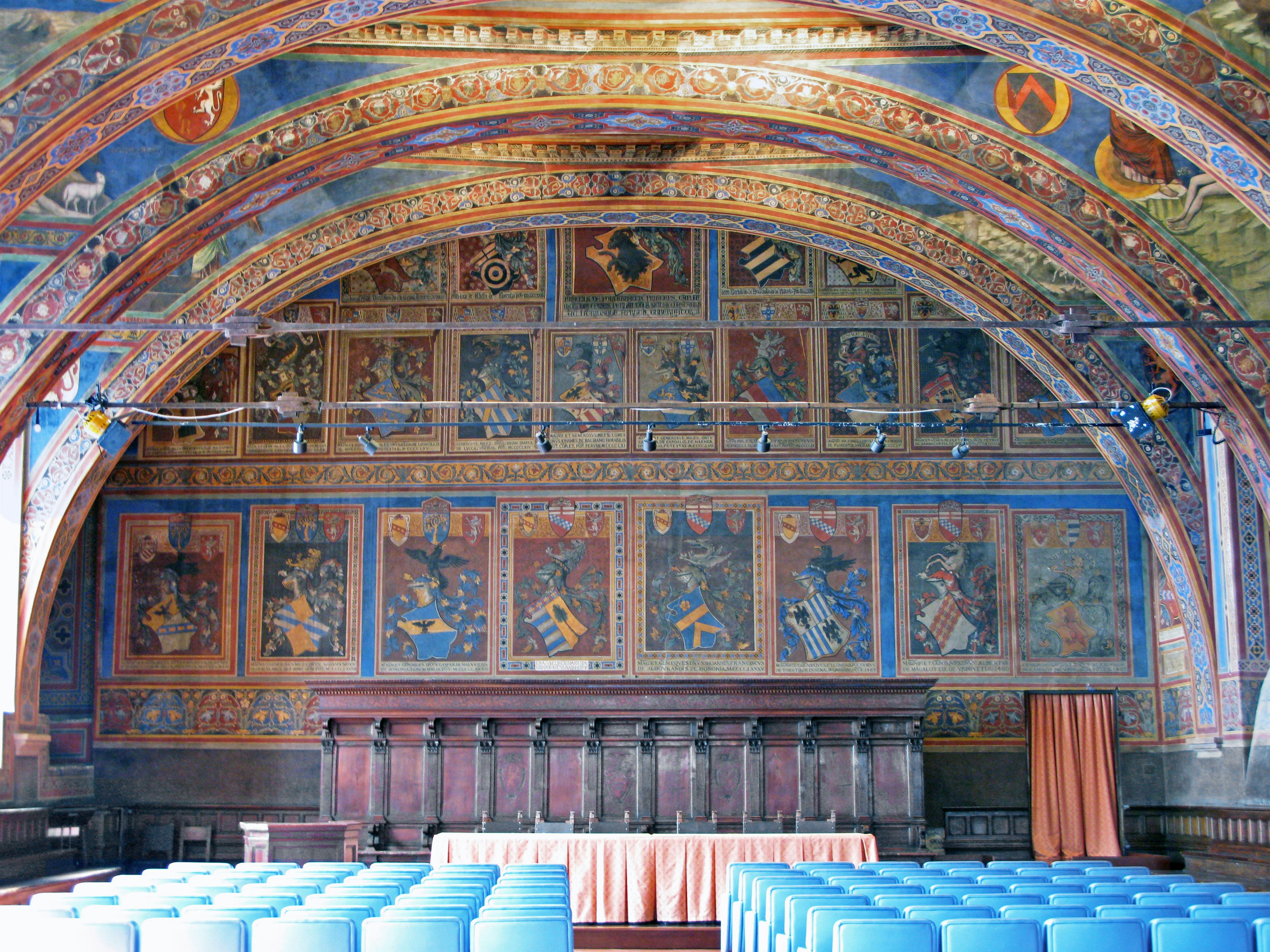 Interior of a historical hall with beautiful decorations featuring a large arched ceiling and colorful murals