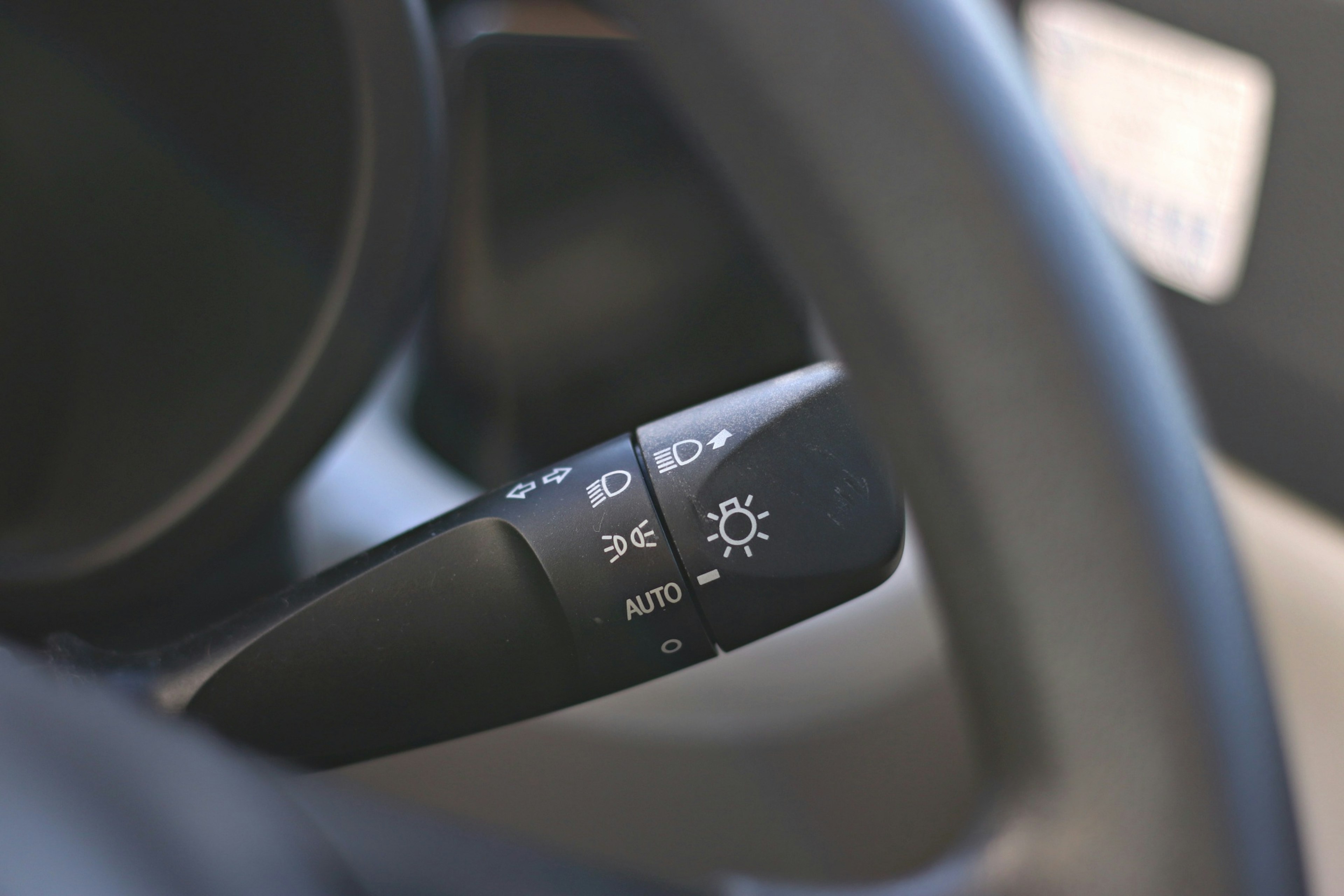 Close-up of a car steering wheel with a light control switch