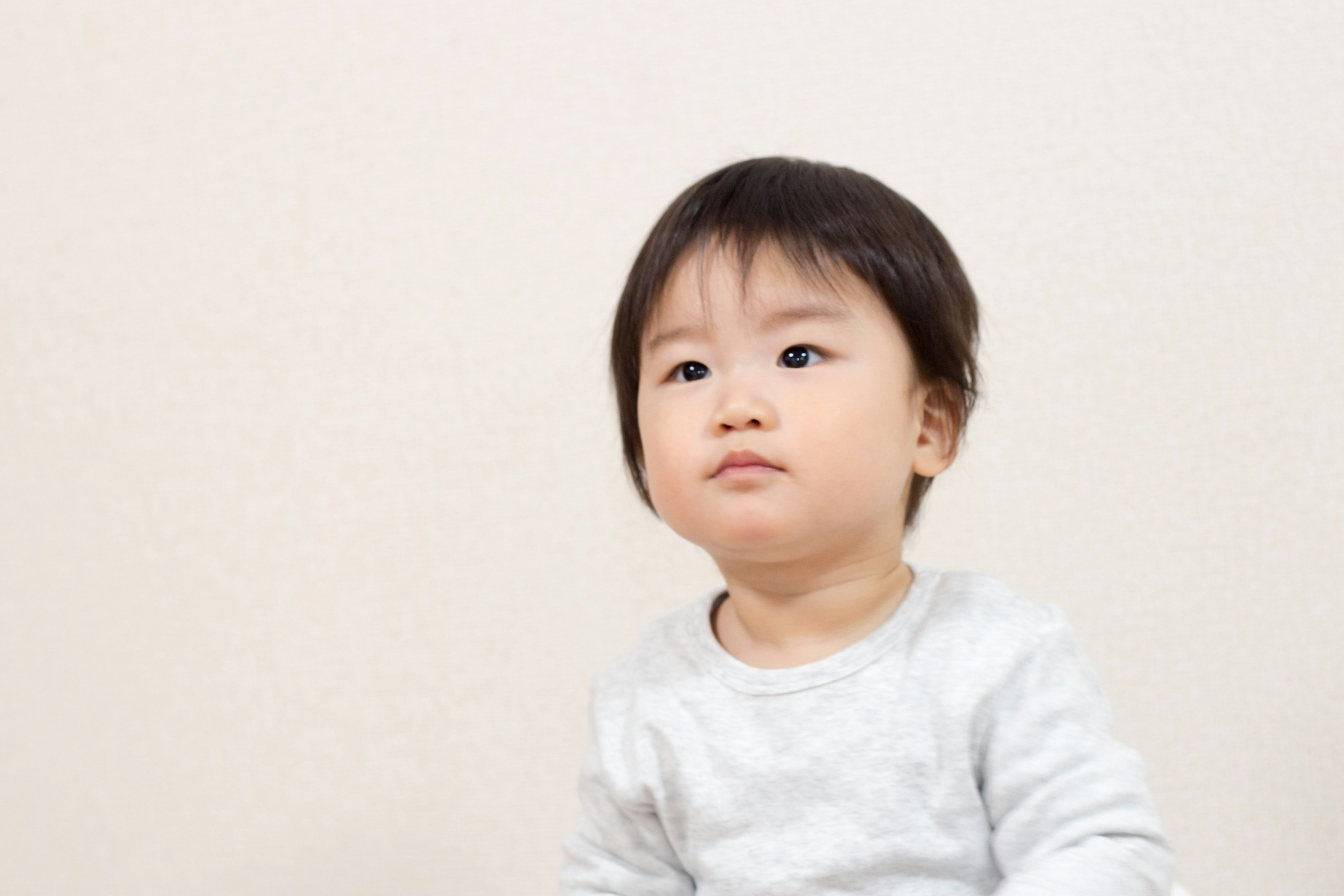 Toddler wearing a gray sweater looking thoughtfully at the front