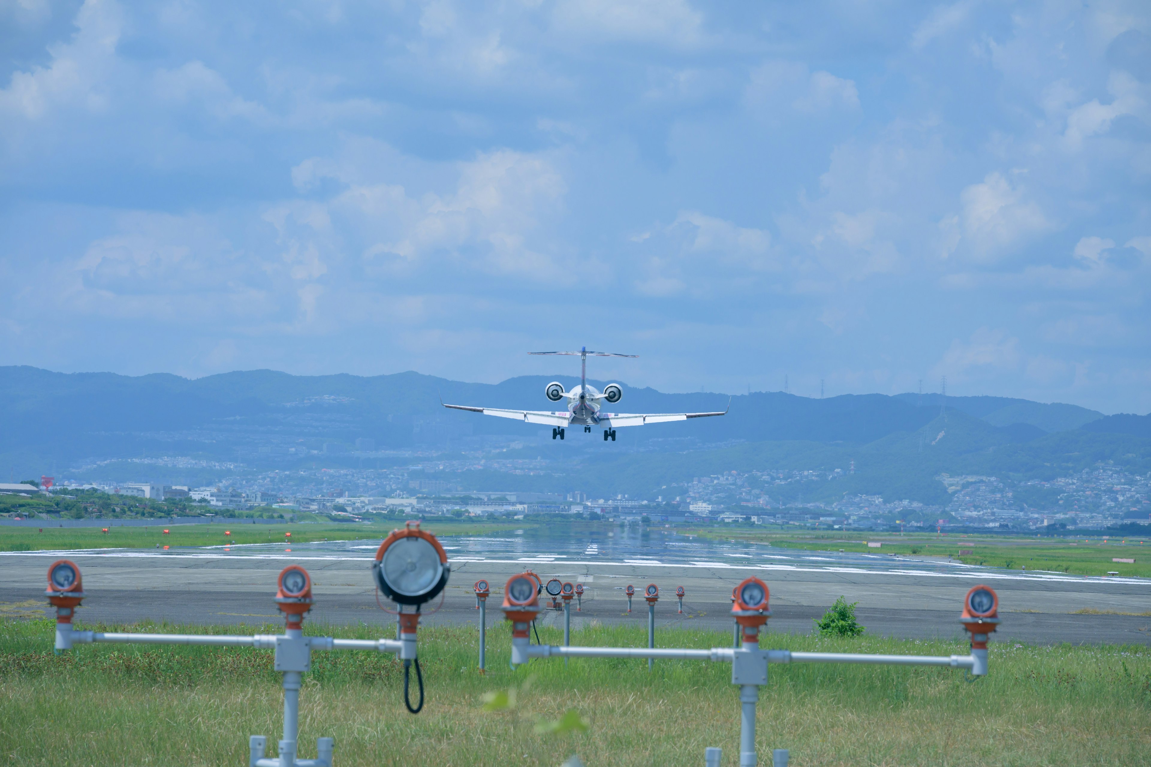 Aircraft landing under blue sky runway markers in the foreground