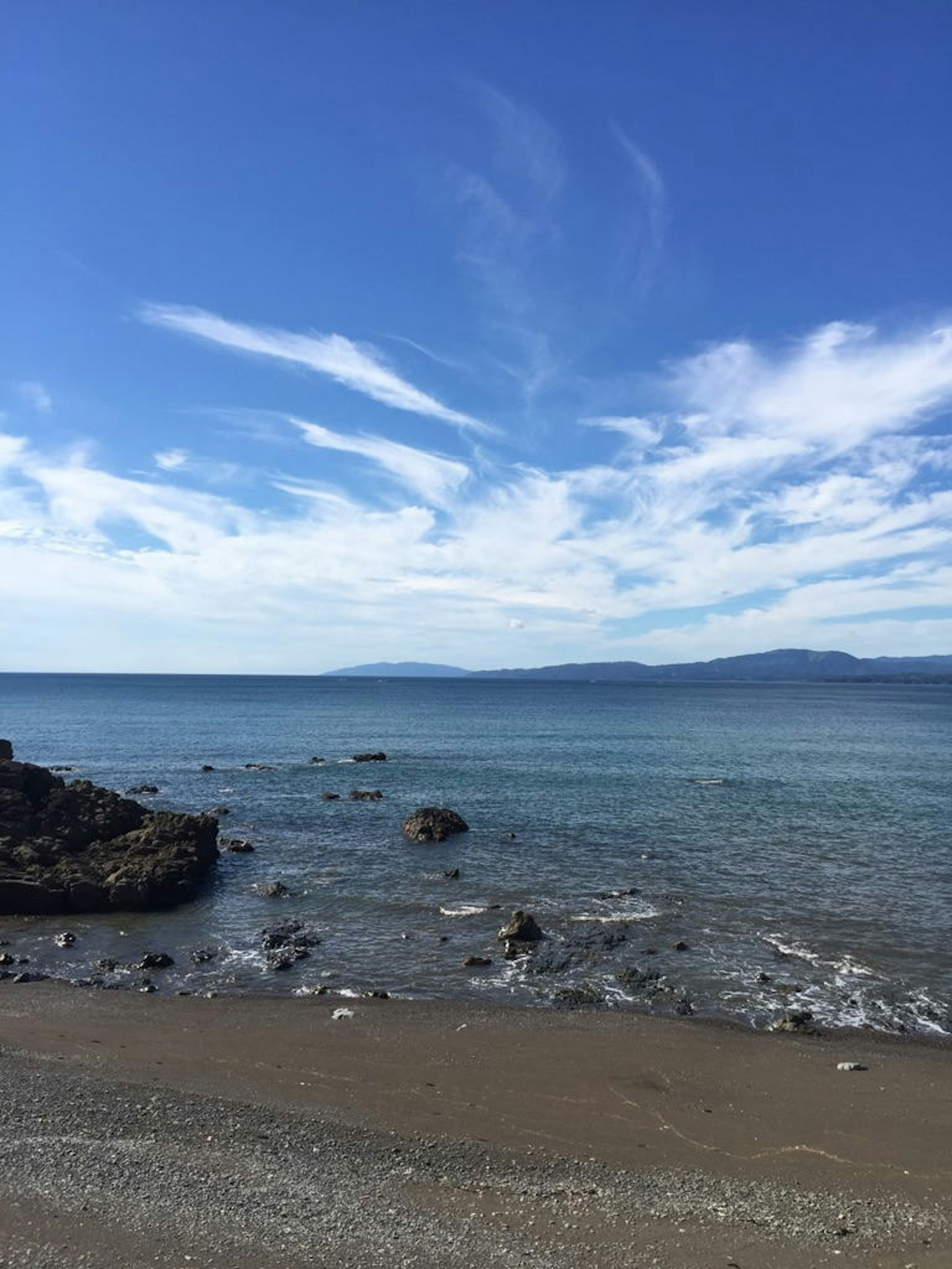 Pemandangan indah langit biru dan laut tenang dengan batu dan pantai berpasir