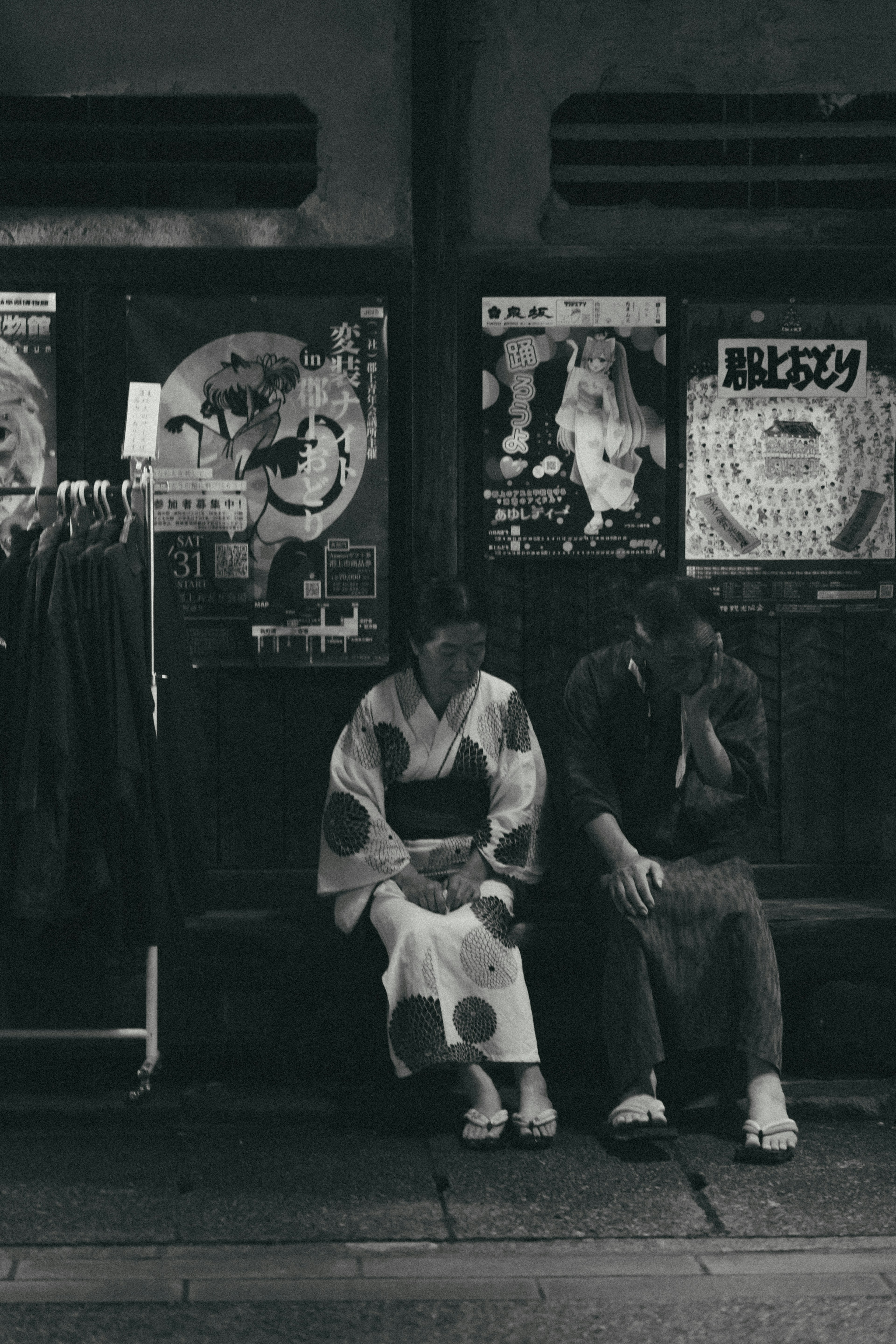 Una foto en blanco y negro de dos personas sentadas frente a carteles vintage