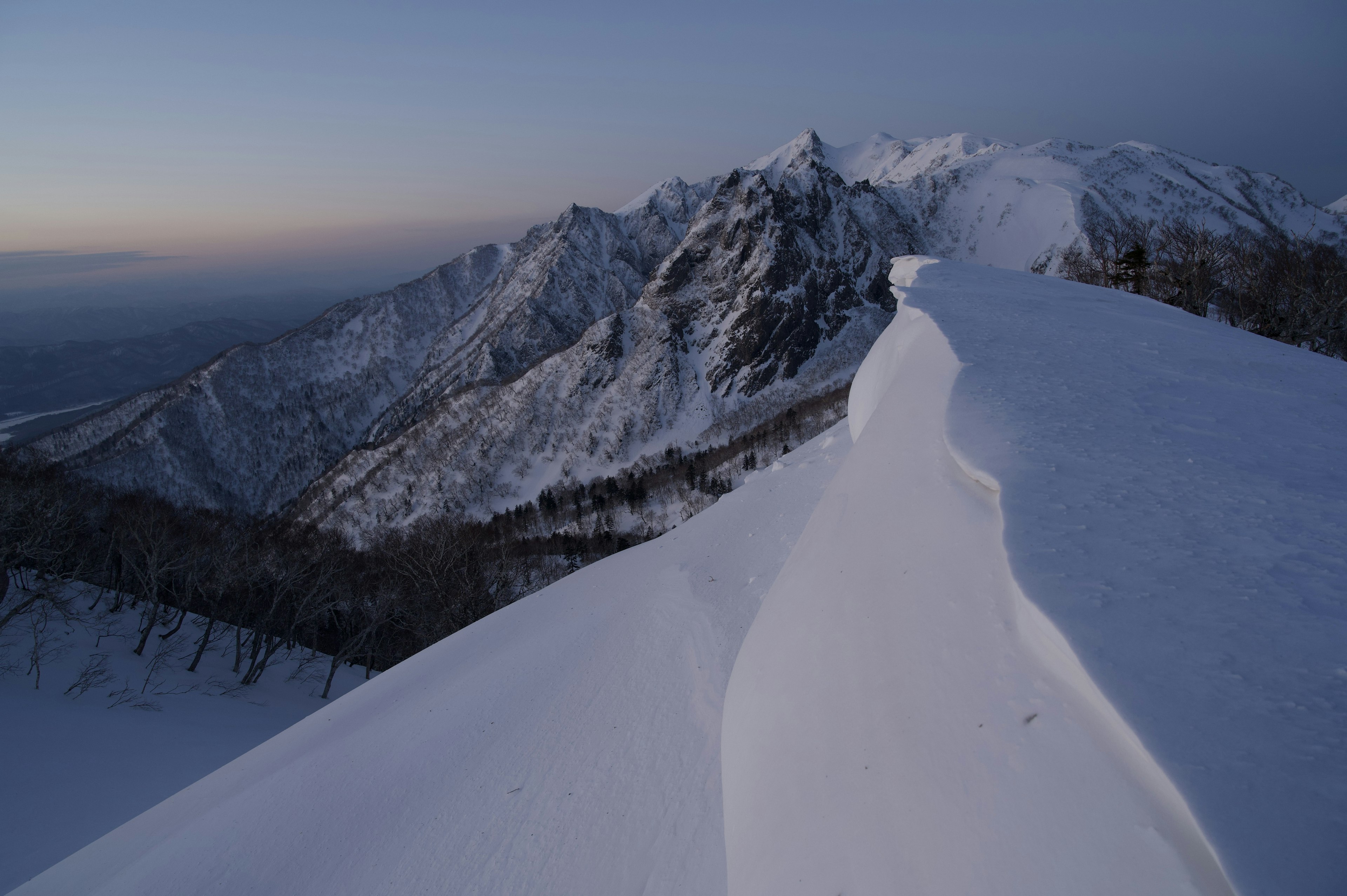 Paisaje montañoso cubierto de nieve con cielo al anochecer