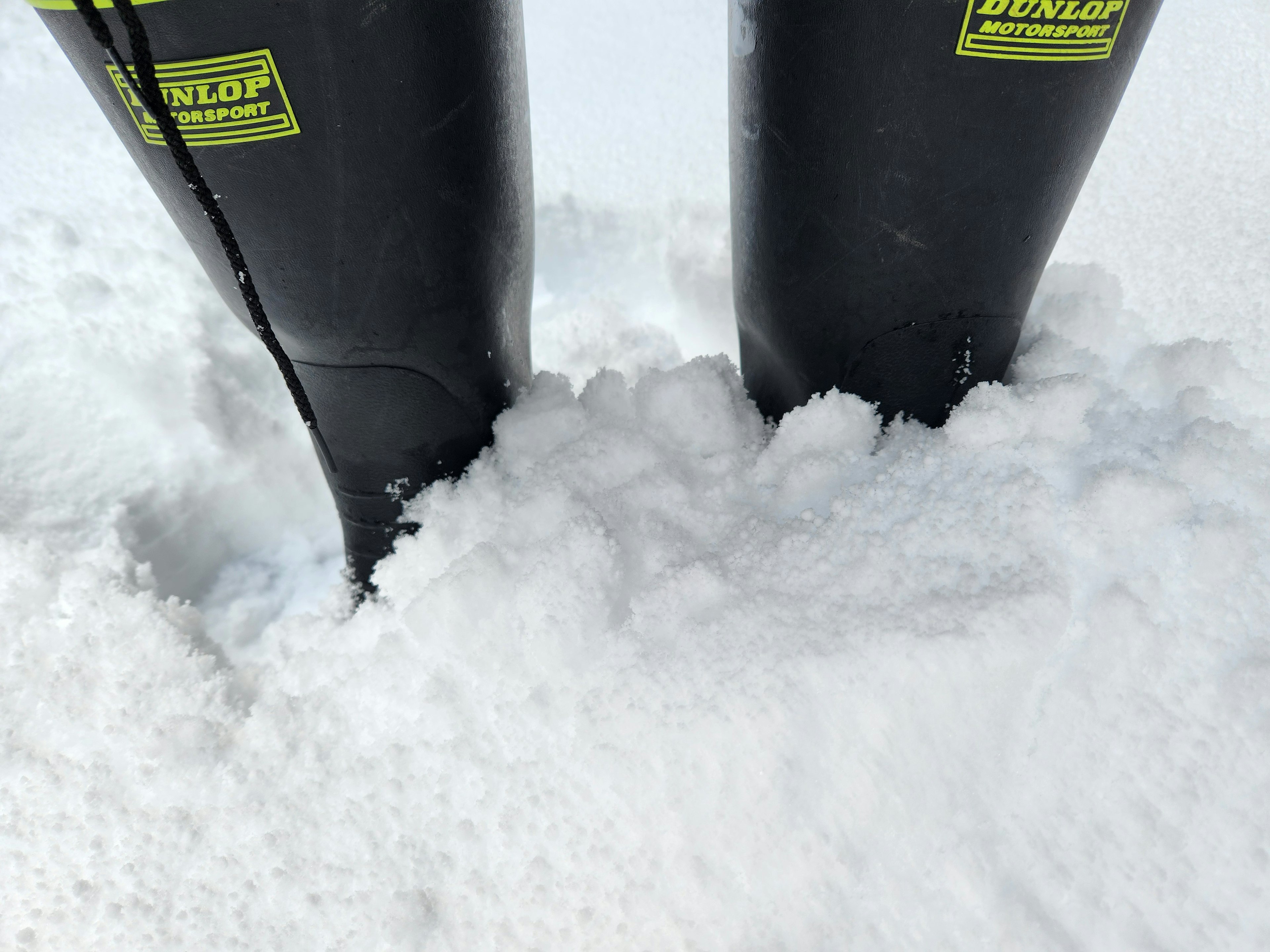 Close-up of black boots partially buried in white snow