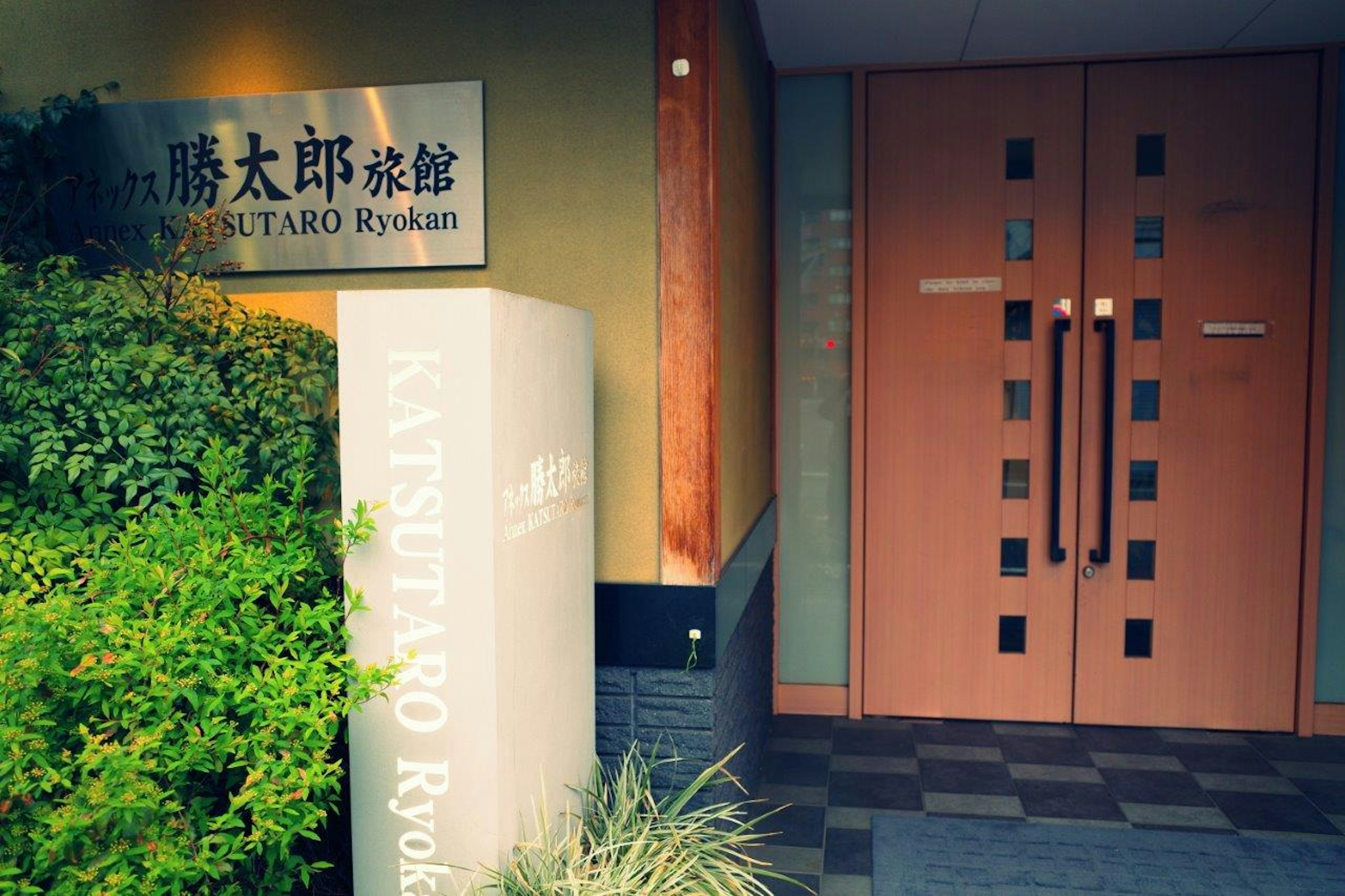 Entrée d'un ryokan japonais traditionnel avec de la verdure et des portes en bois