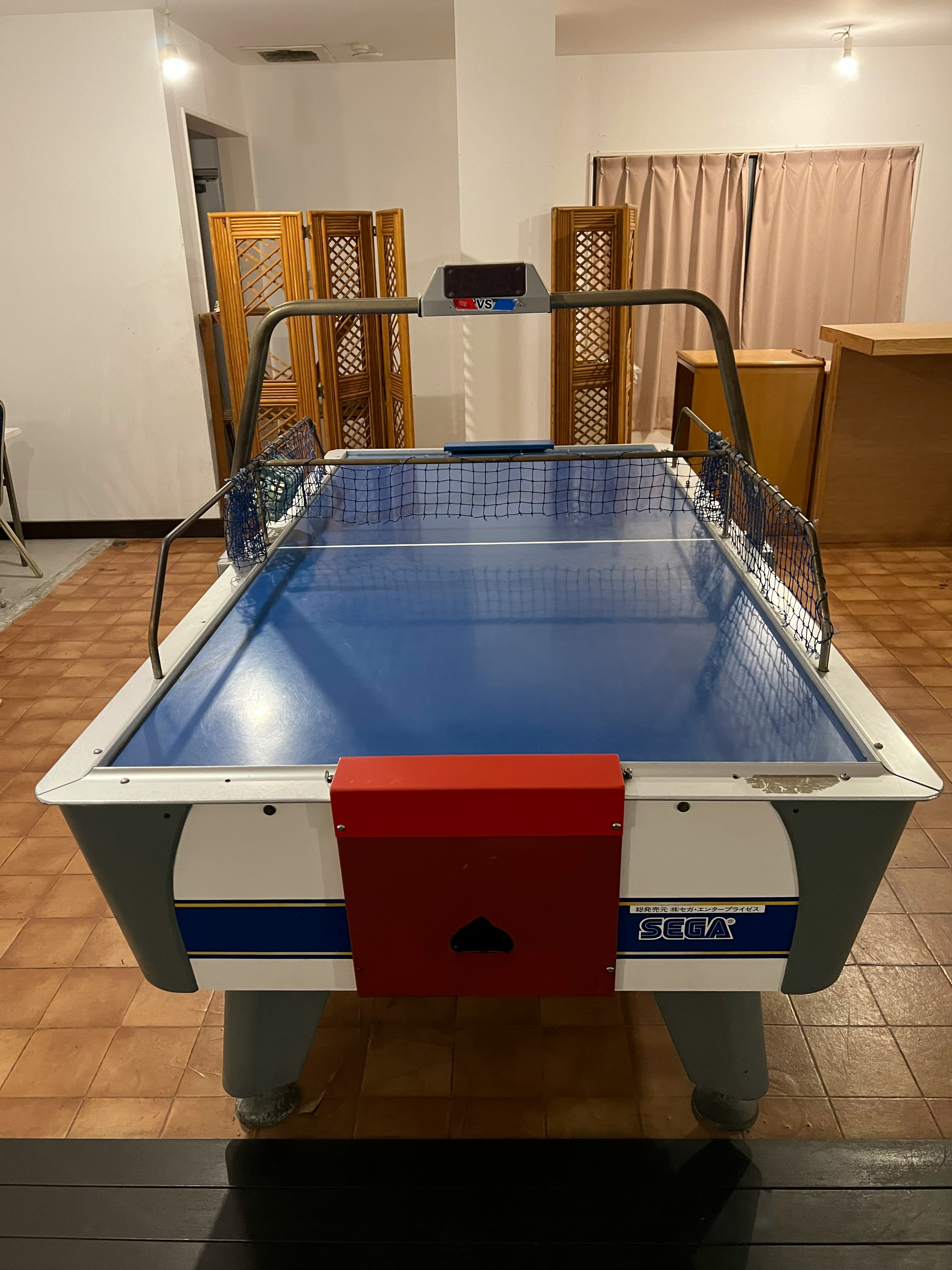 Table de air hockey avec une surface de jeu bleue et une zone de but rouge