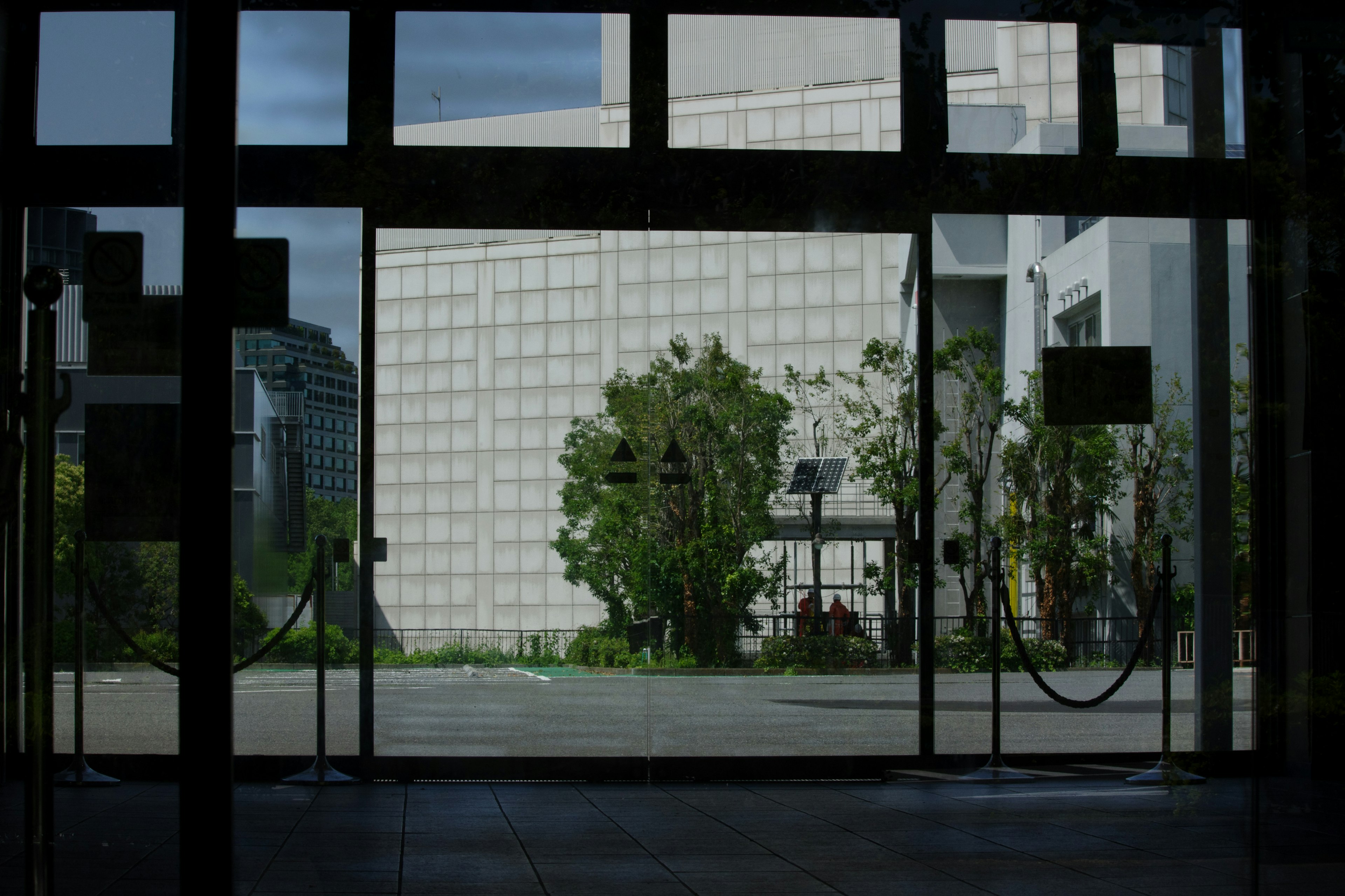 Blick durch transparente Glastüren auf einen Garten und ein modernes Gebäude