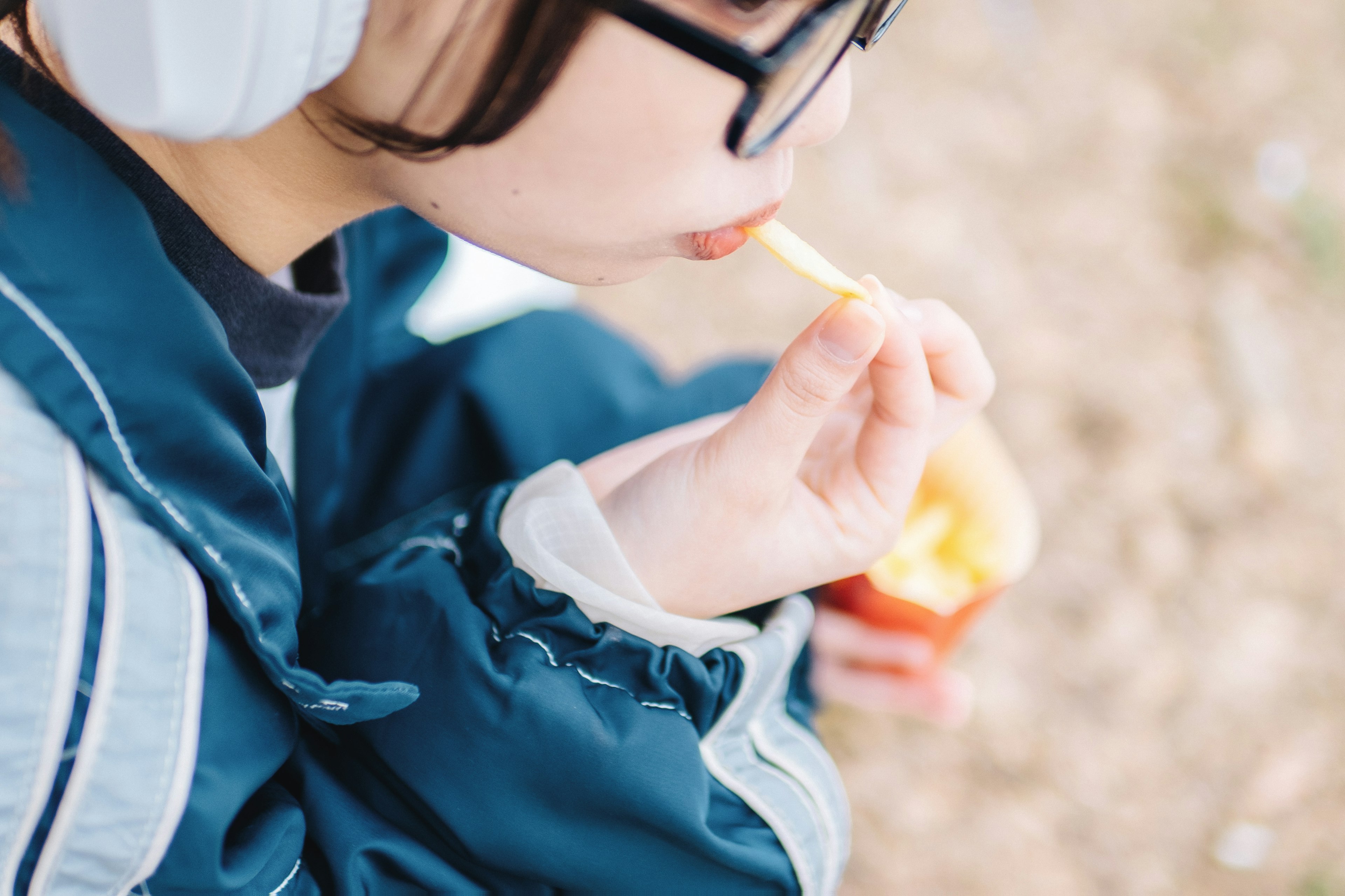 女の子がスナックを食べている様子　青いジャケットとイヤフォンを着用