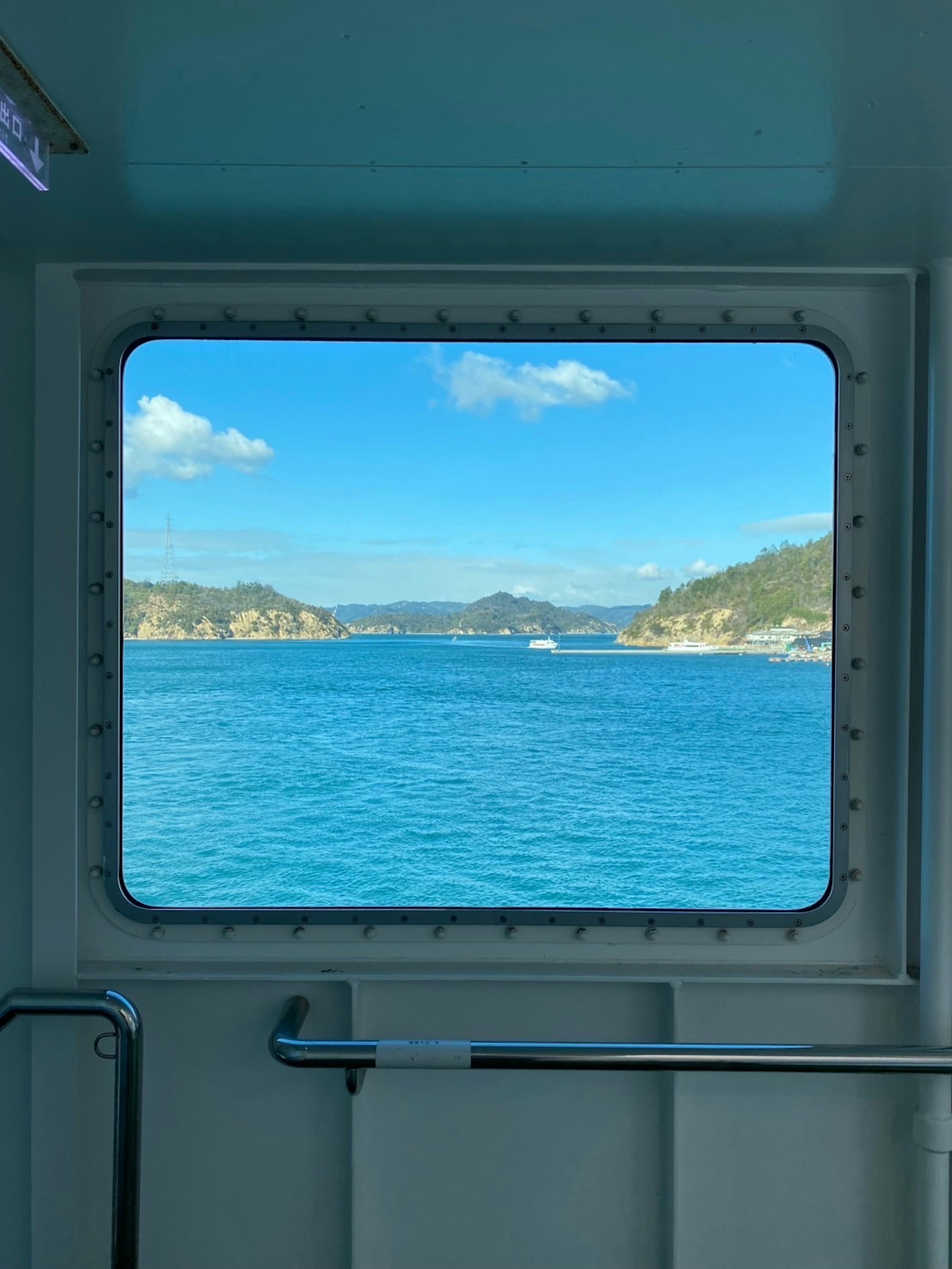 青い海と緑の丘が見える船の窓からの景色