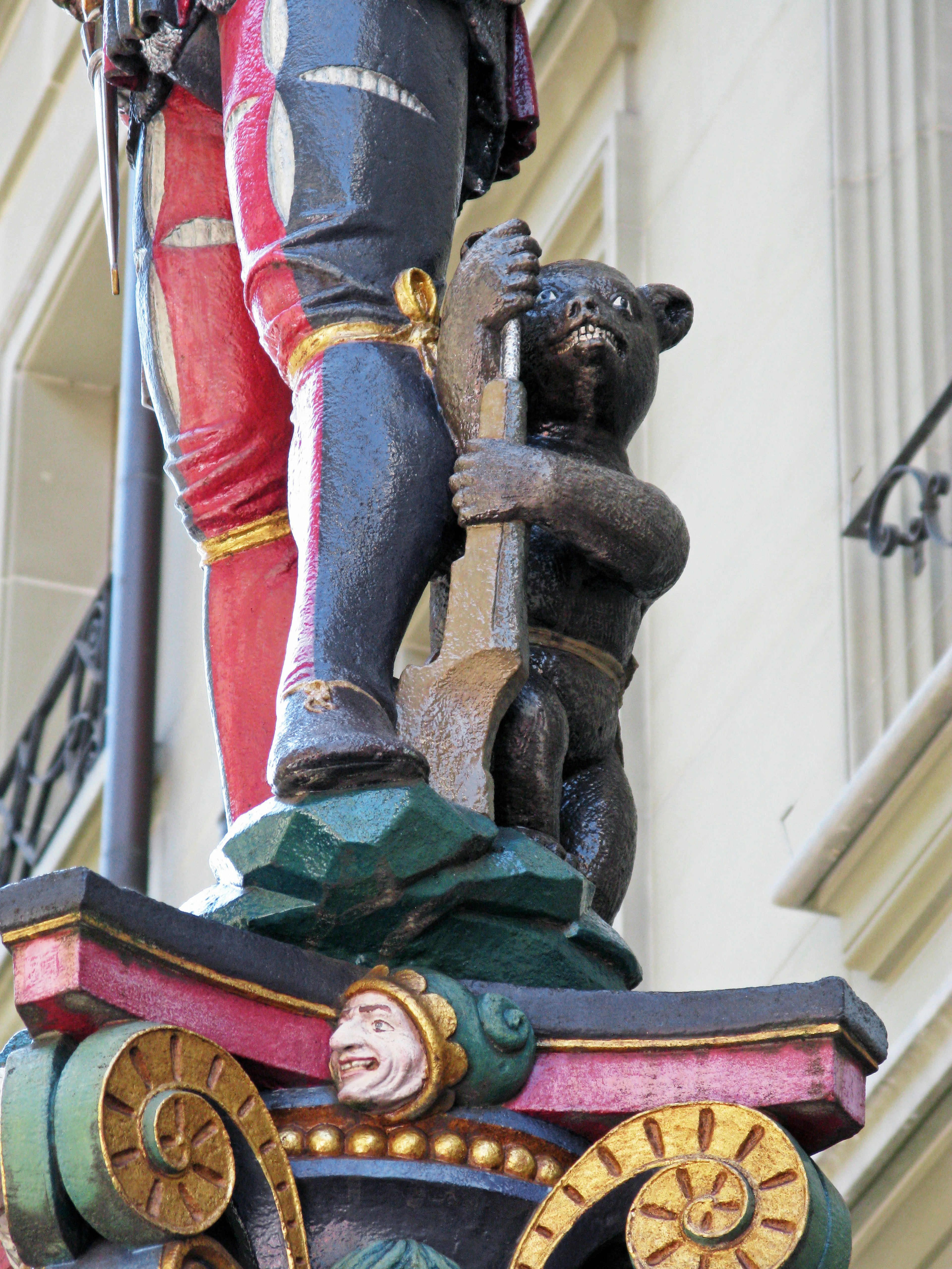 Ein hölzerner Bär, der sich an einem Pfosten in einer dekorativen Skulptur festhält