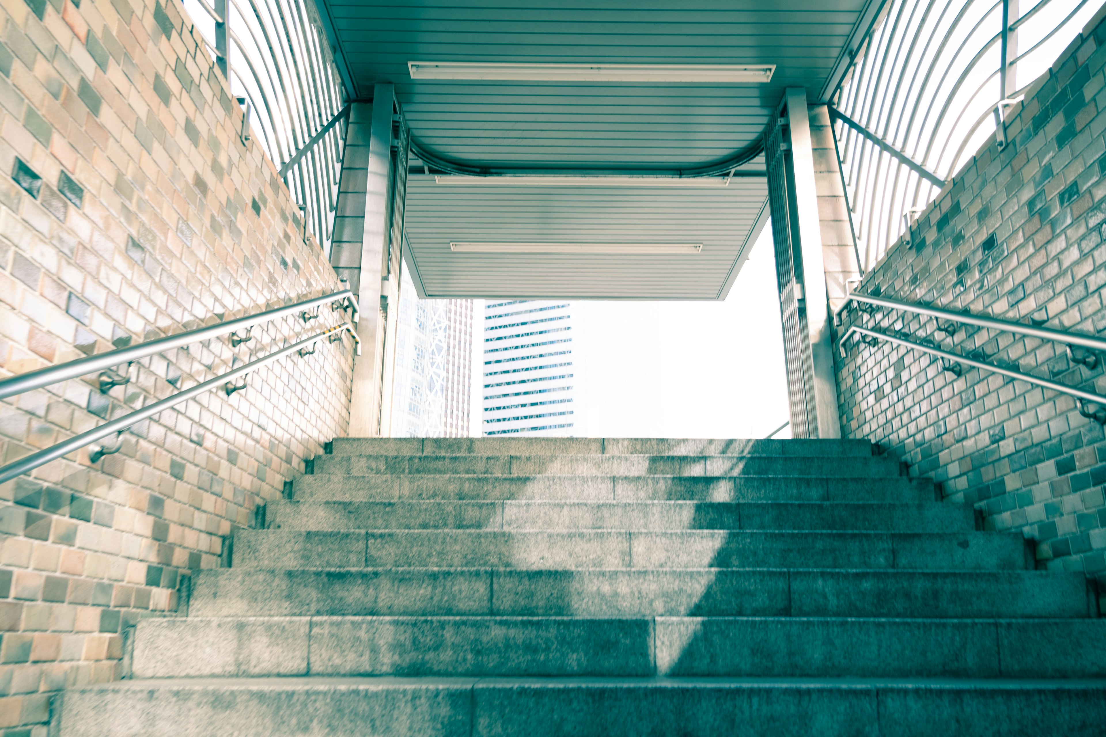 Photo from the perspective of stairs leading up Bright lighting and brick walls are featured