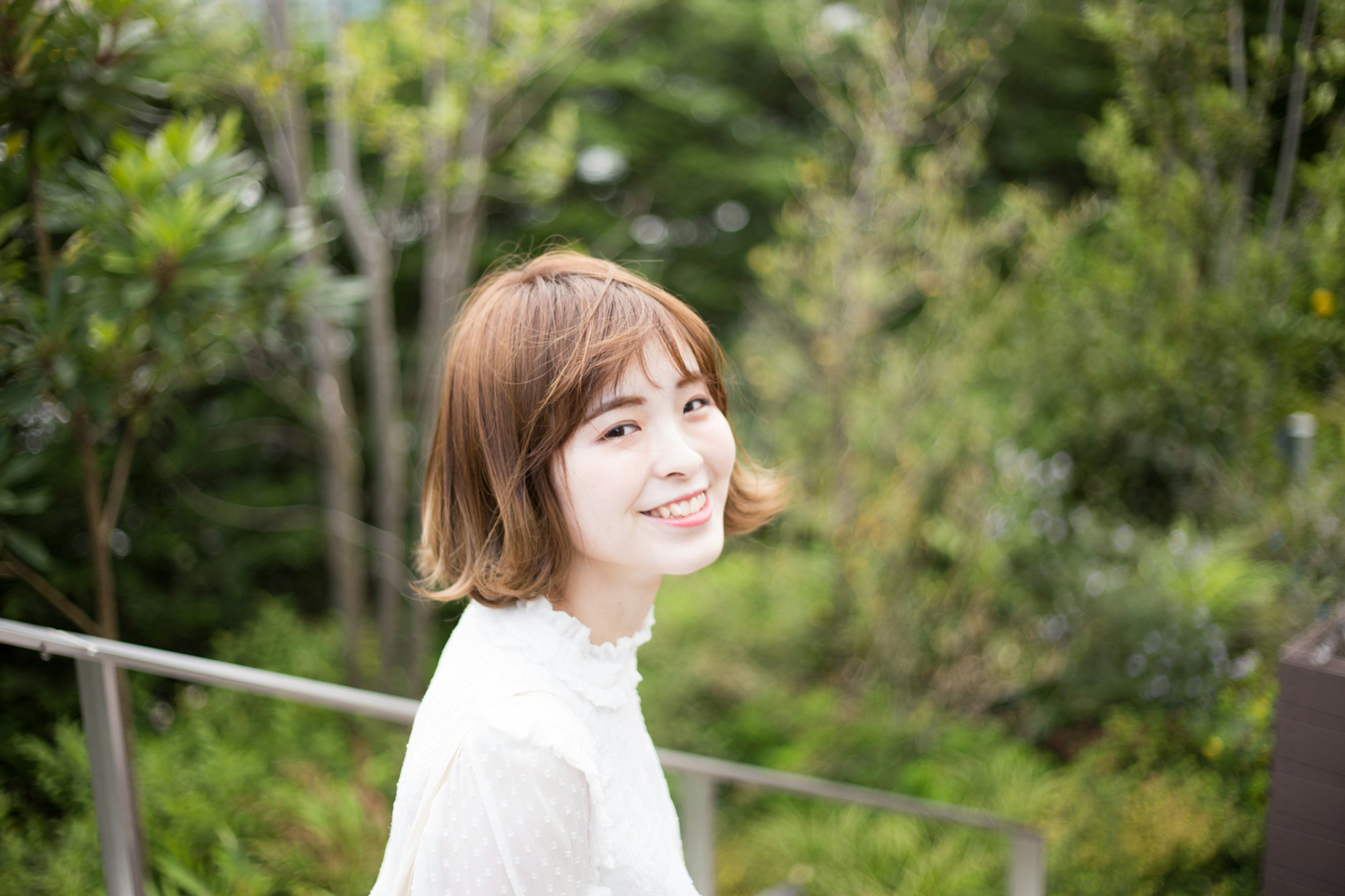 Portrait of a smiling woman in a park with greenery