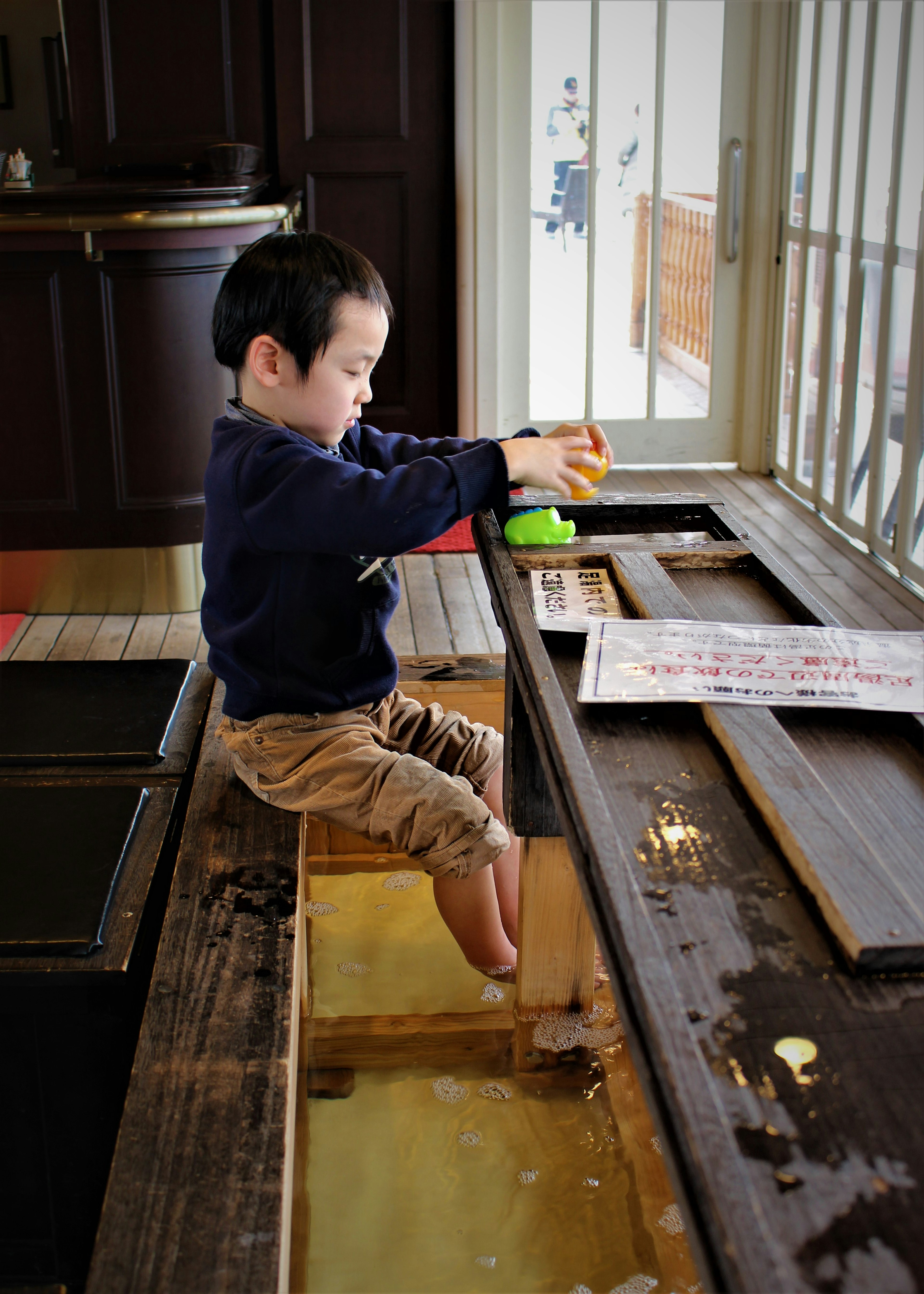 Un niño jugando en una mesa de madera con agua