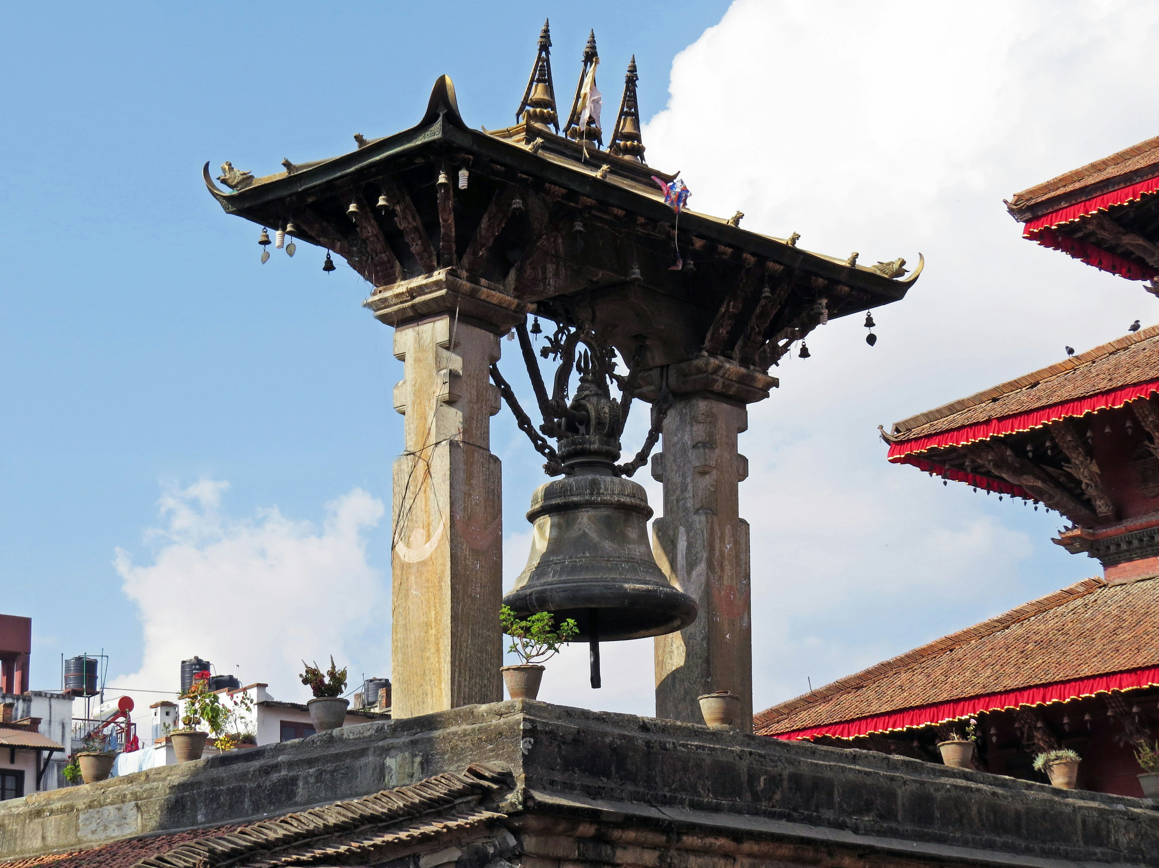 Campana tradizionale e tetto ornato di un tempio nepalese