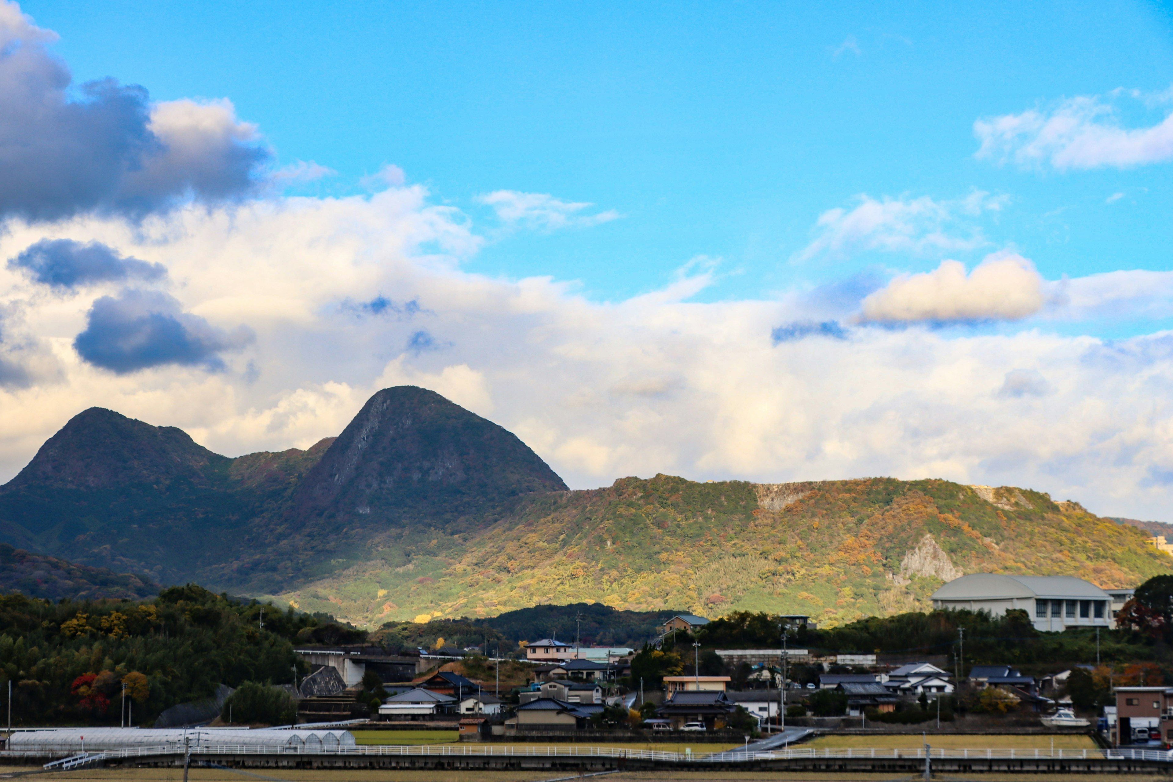 青空の下で山々がそびえ立つ風景と住宅地