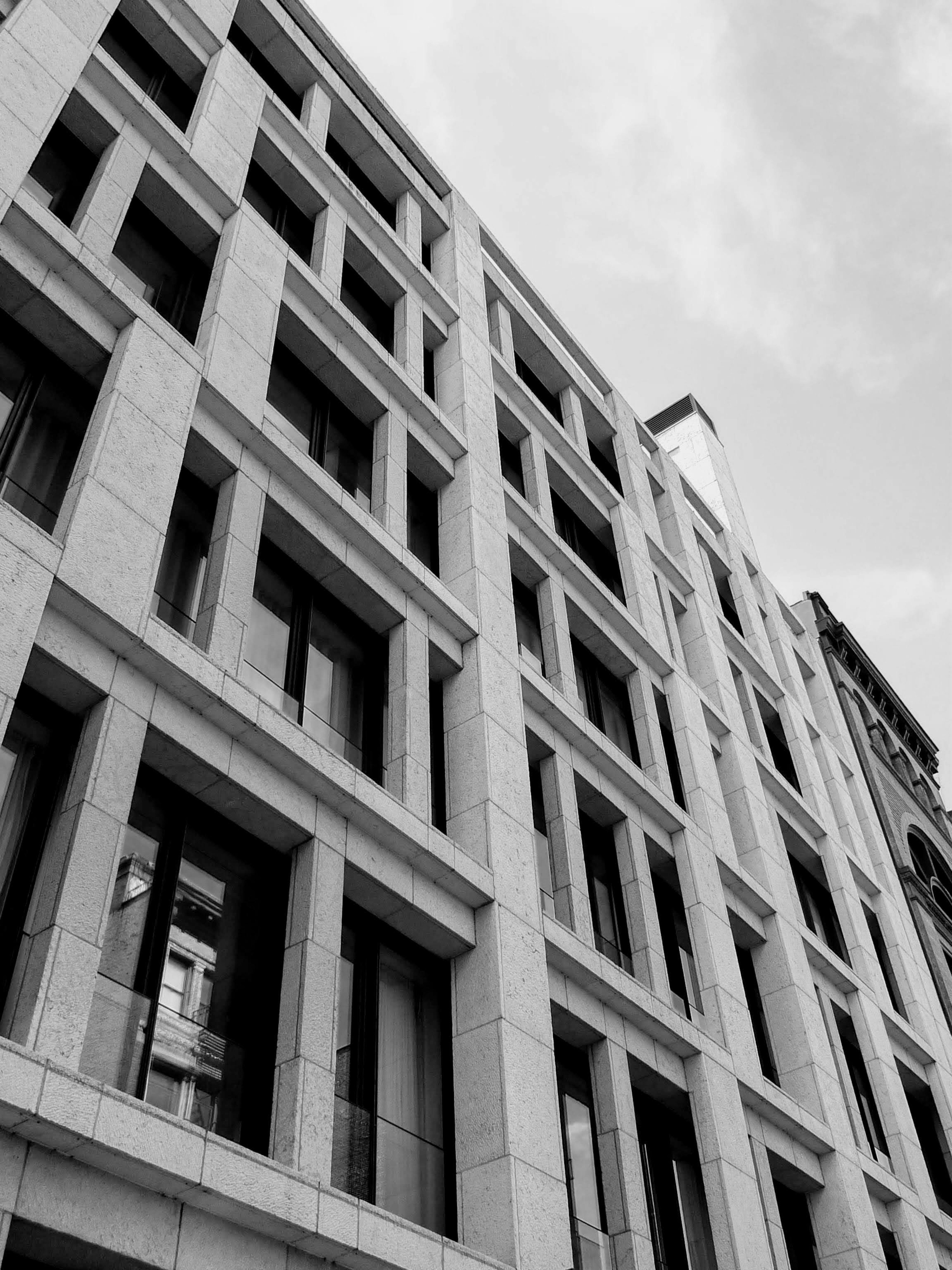 Fachada de un edificio moderno capturada en blanco y negro con ventanas y diseño geométrico