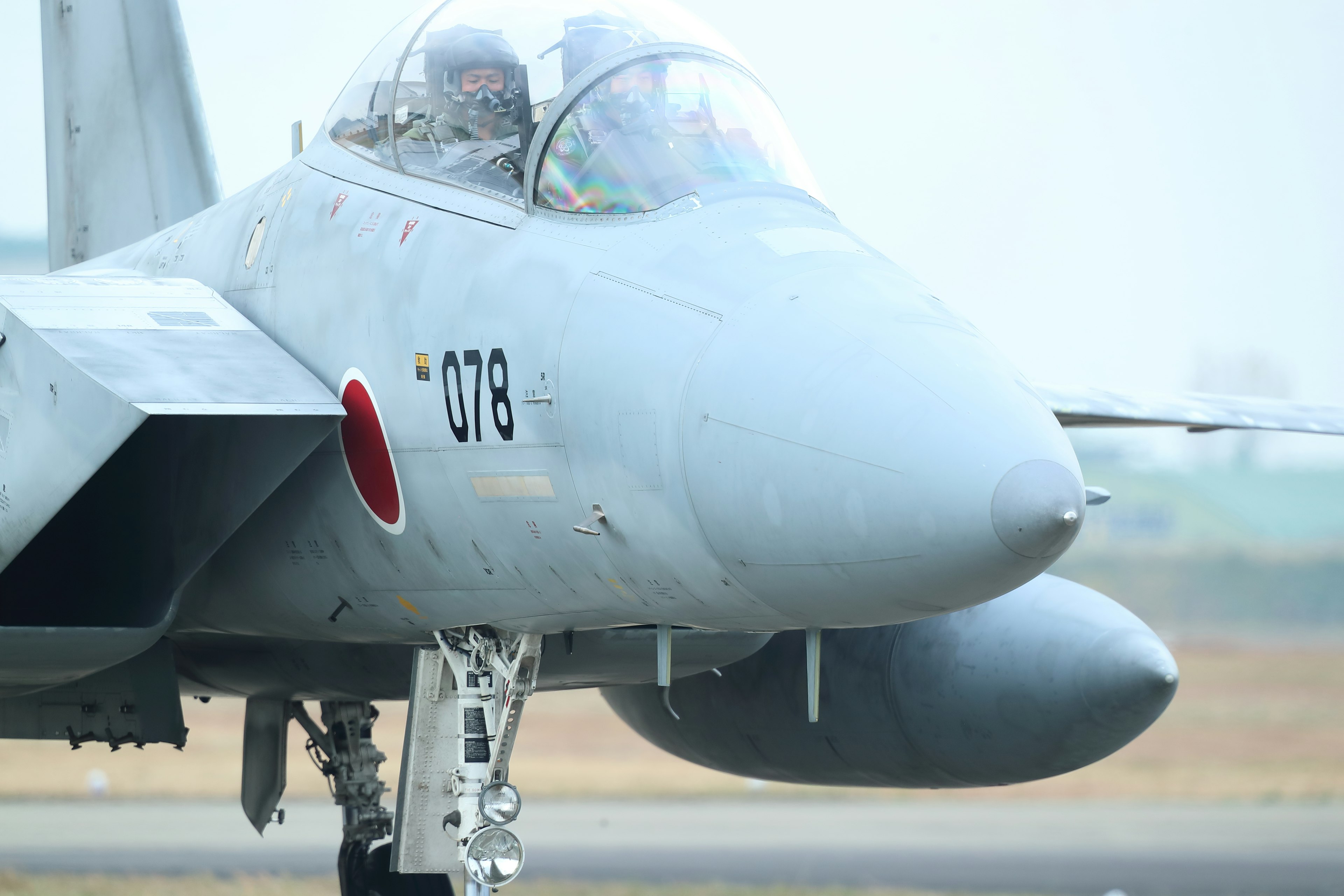 Seitenansicht eines japanischen Kampfjets mit Sicht auf das Cockpit und die Piloten