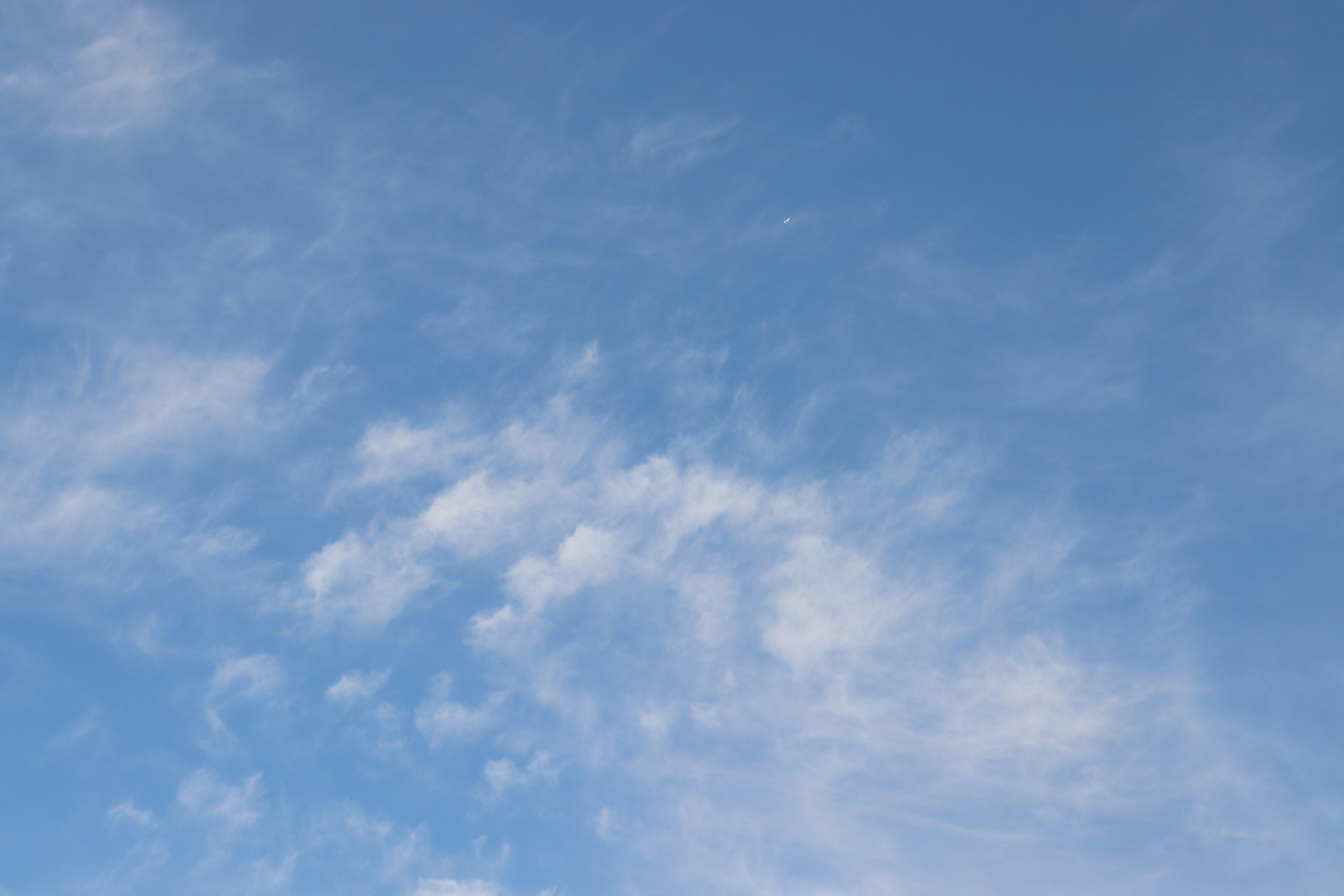 Clear blue sky with soft white clouds