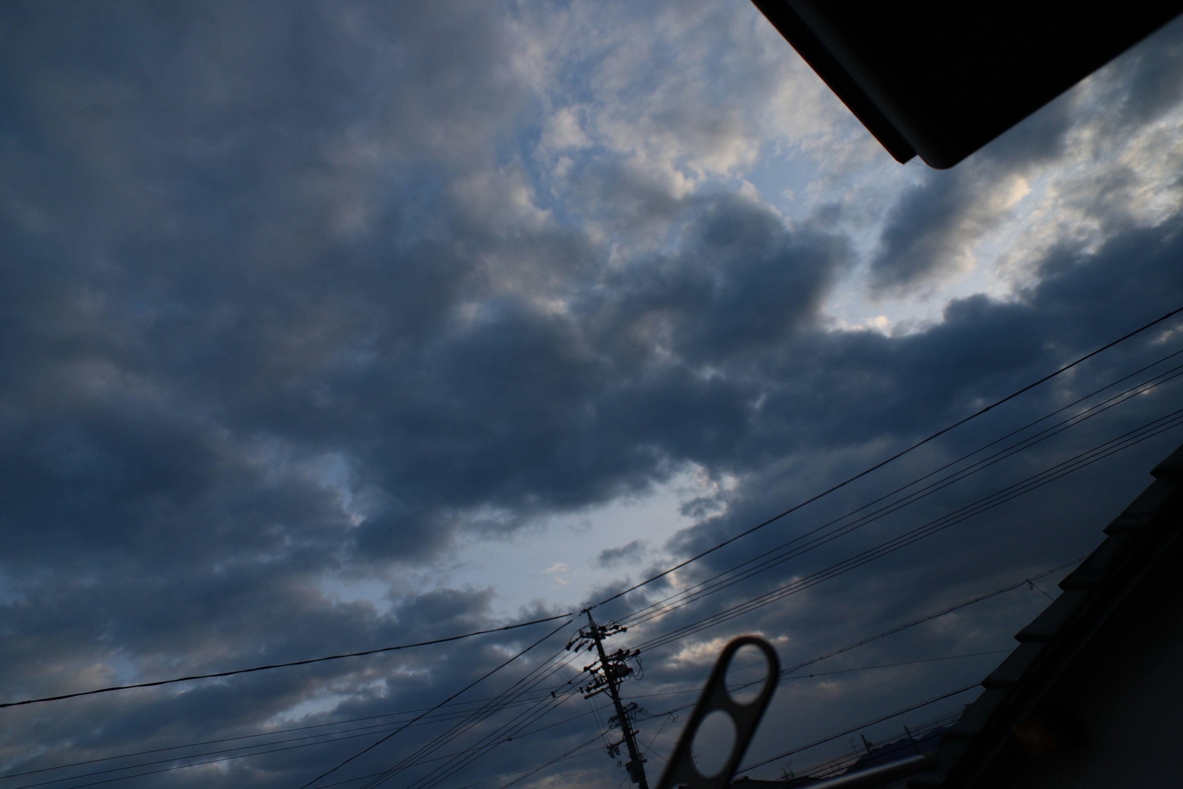 Langit sore dramatis penuh awan dan siluet tiang listrik